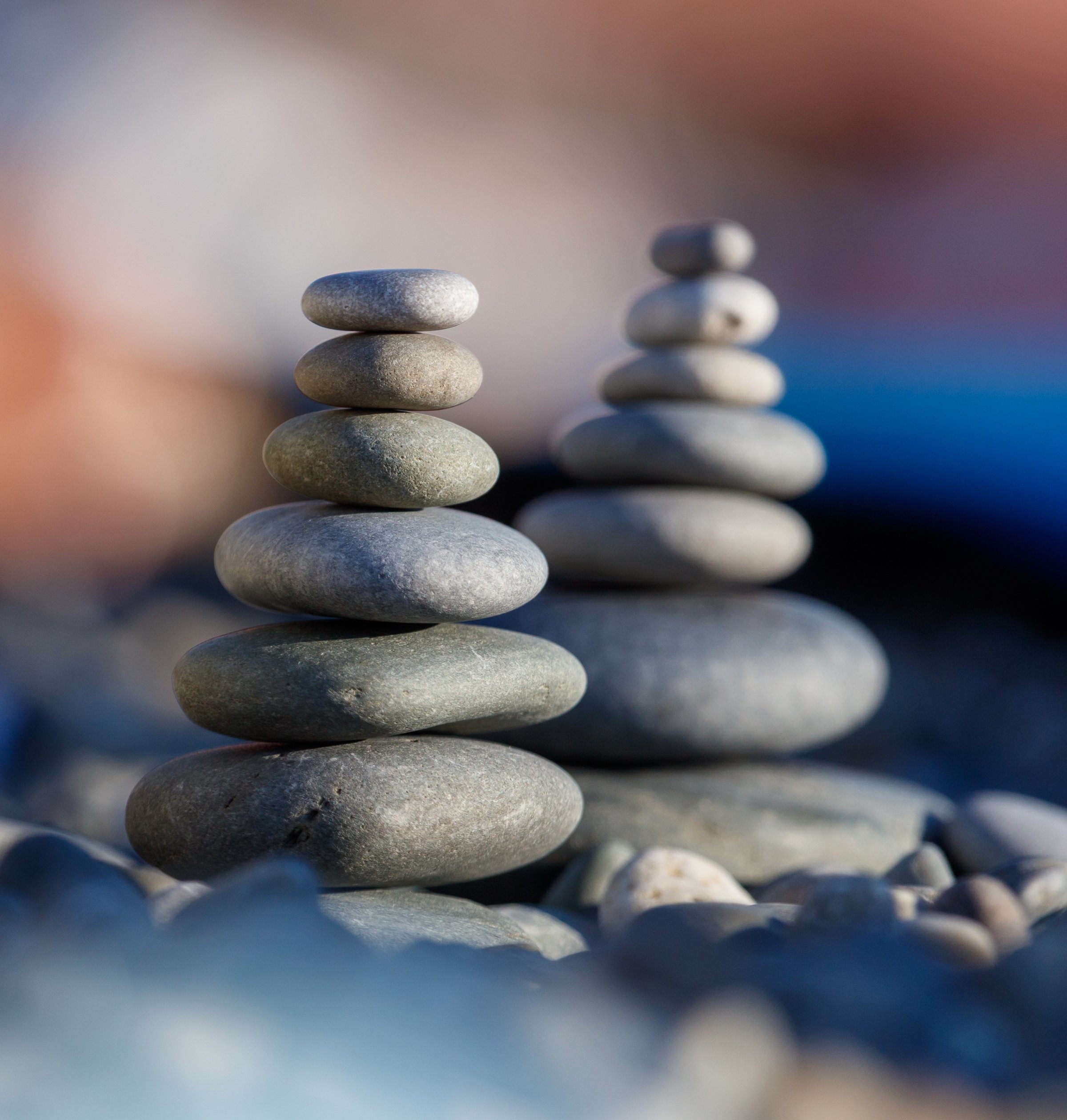 Two stacks of rocks are on the ground. The rocks are gray and are stacked on top of each other