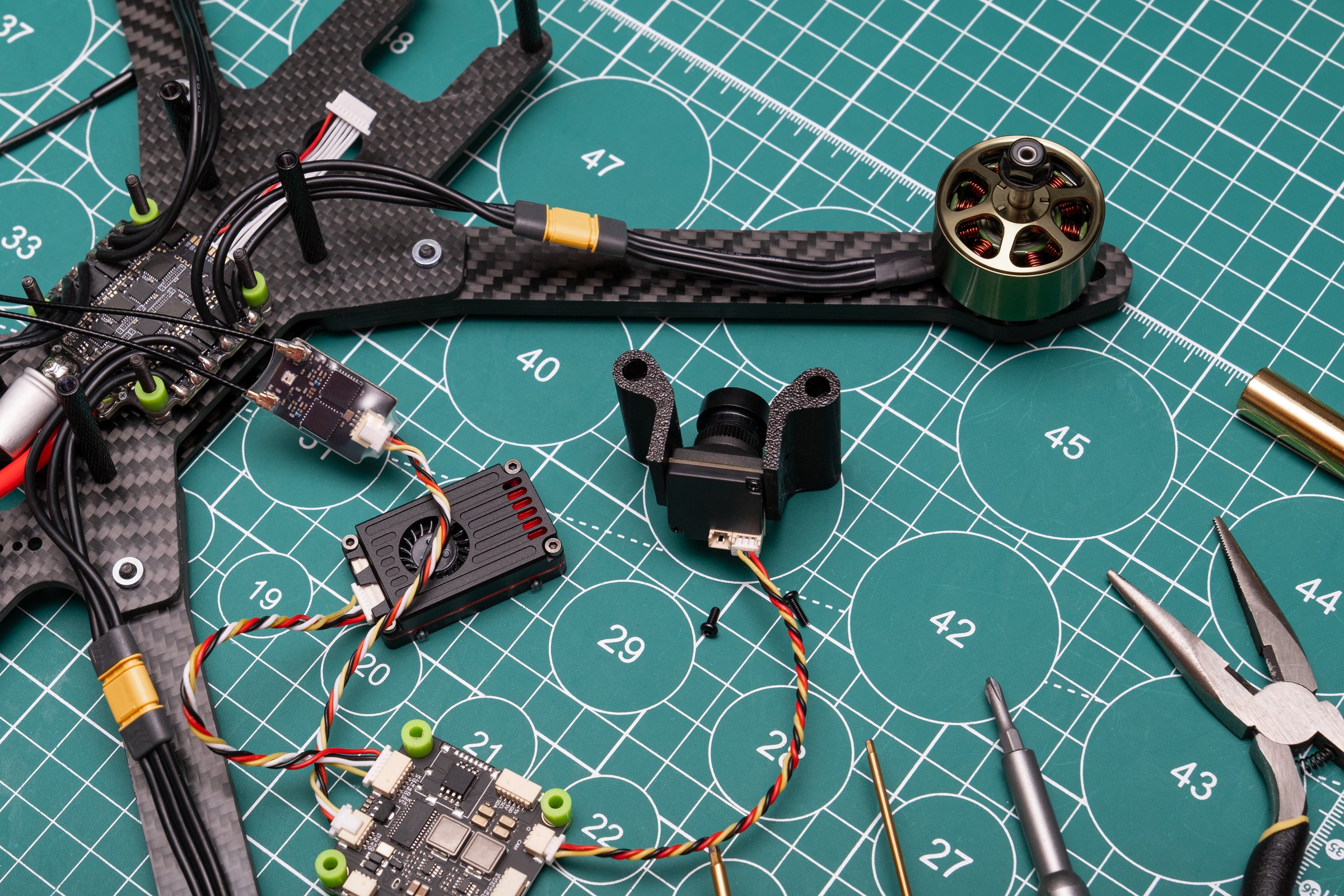 disassembled sport FPV drone body with an electric motor lies on a work table, alongside DIY electronic speed controllers, ready for flight assembly.