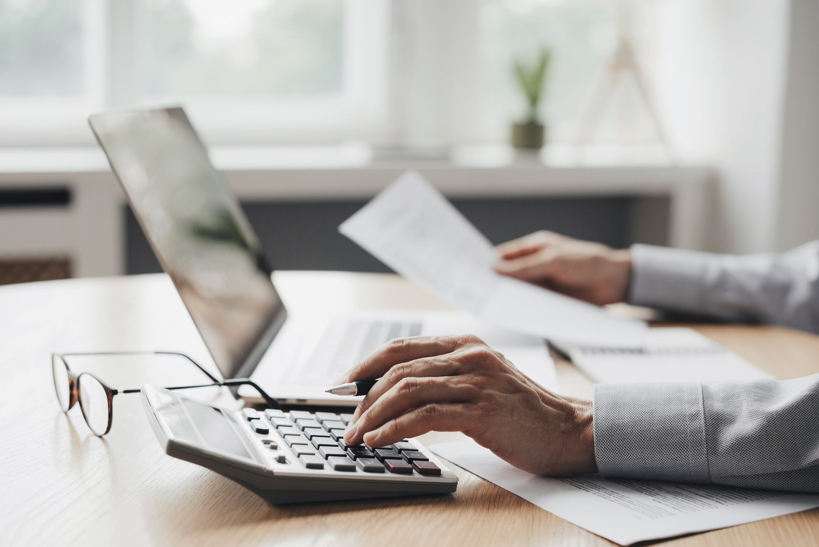Man using calculator with computer laptop, budget and loan paper in office. Business accounting, bills, home budget, tax, savings, finances, economy, audit, debt concept