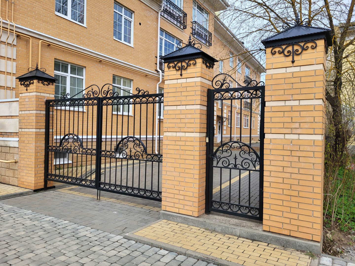 There are beautiful wrought iron carved gates and a gate between the brick columns
