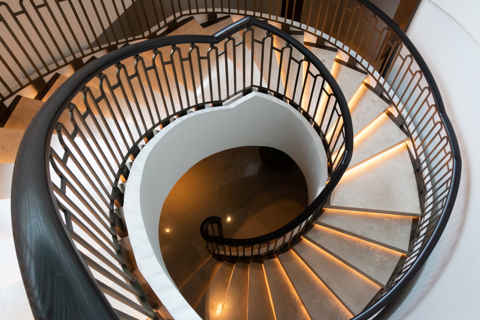 Scala a chiocciola in ferro battuto elegante con illuminazione sui gradini