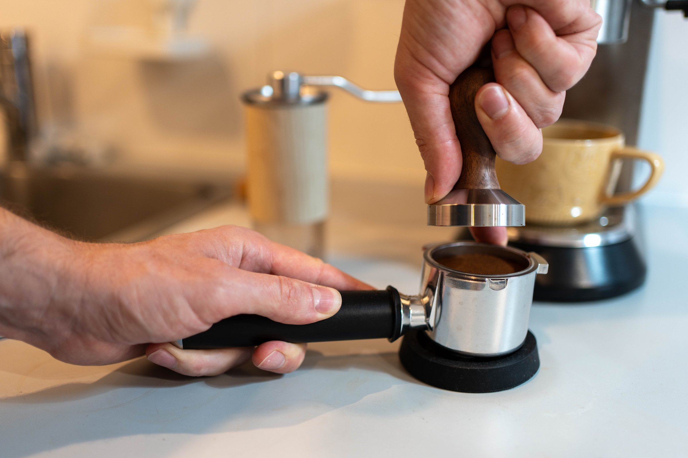 Close-up of a barista carefully tamping ground coffee into a portafilter