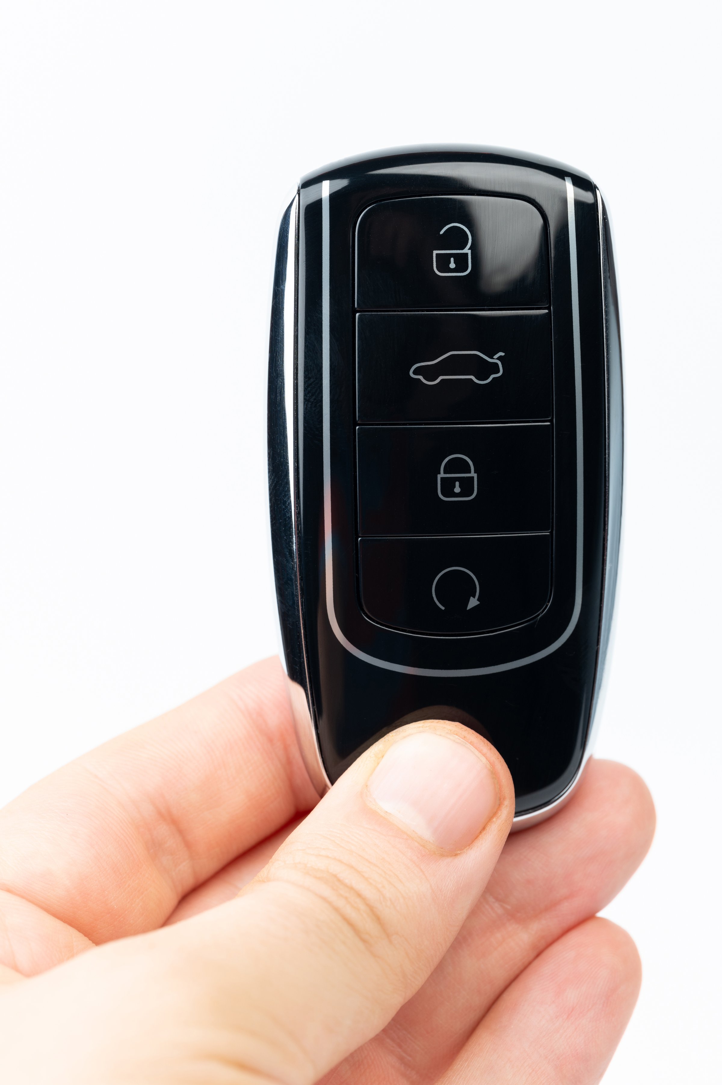 Hand hold black car key isolated on white studio background close up view