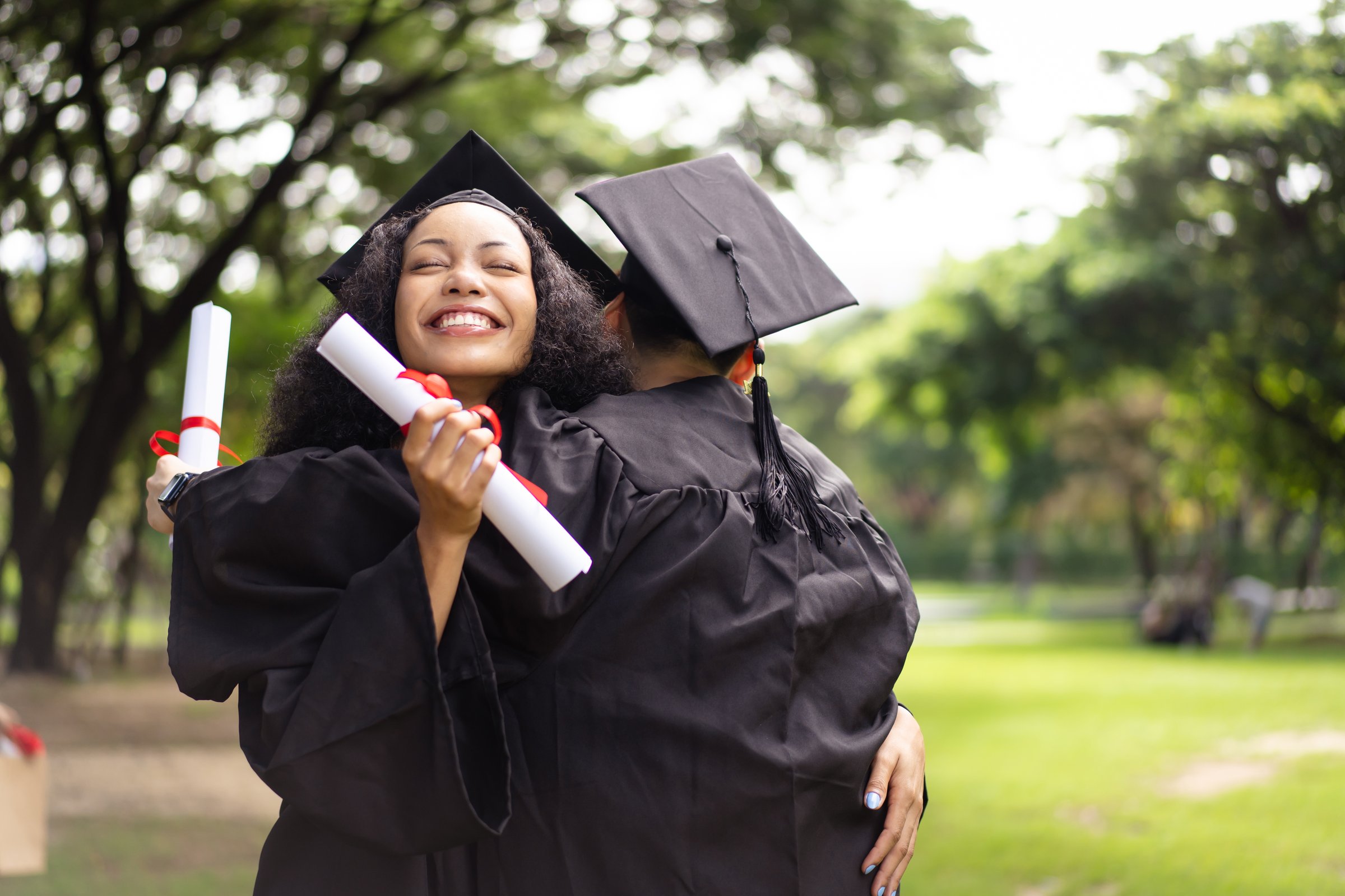 Group of students in graduation gown has an excited and delighted expression as they receive their diploma upon graduating from university. Diverse student feel proud about academic achievement.