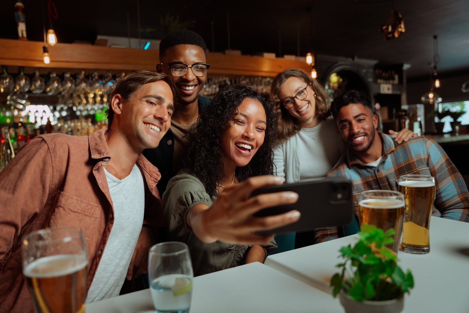 Group of young adult friends eating dinner at restaurant taking selfie with cellular device. High quality photo