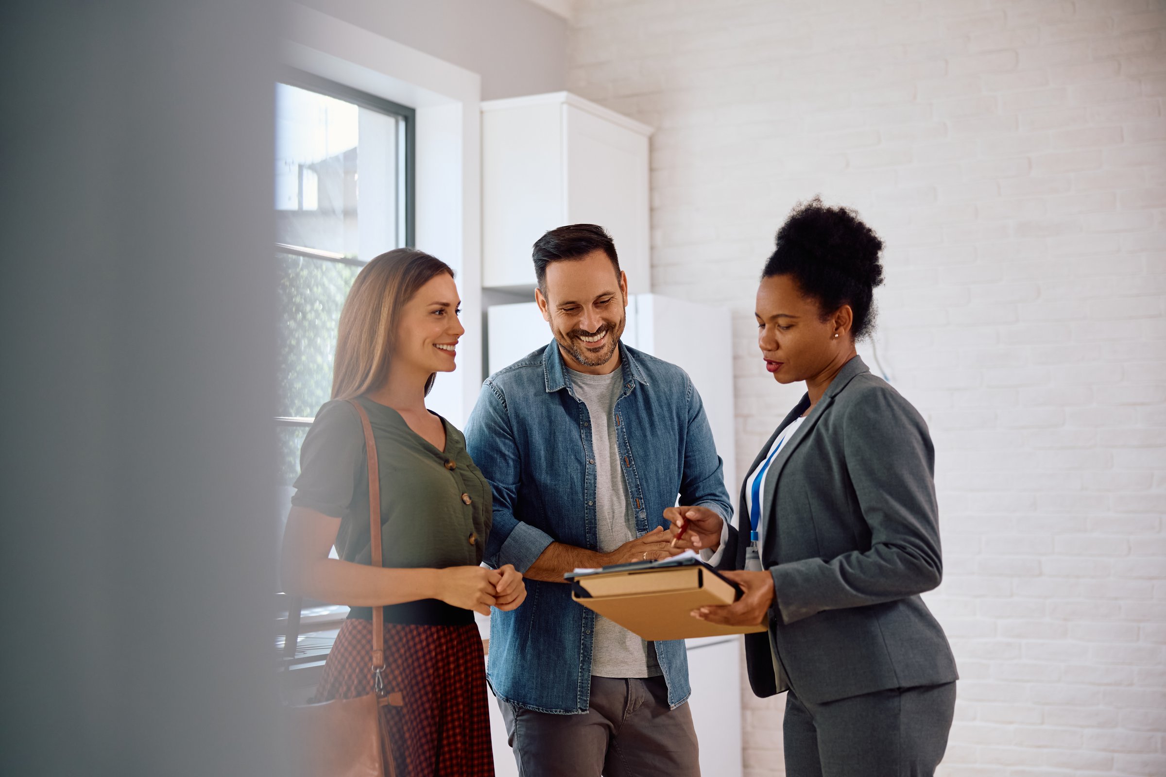 African American real estate agent and potential buyers going through paperwork in new house.