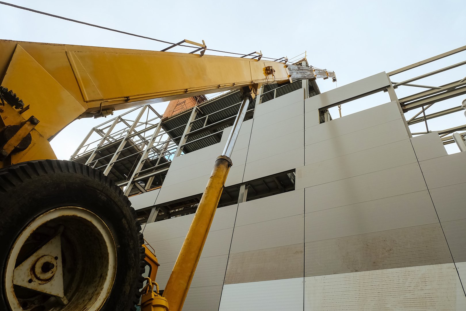 Construction of a production building workshop. Close-up of a truck crane boom from bottom to top.
