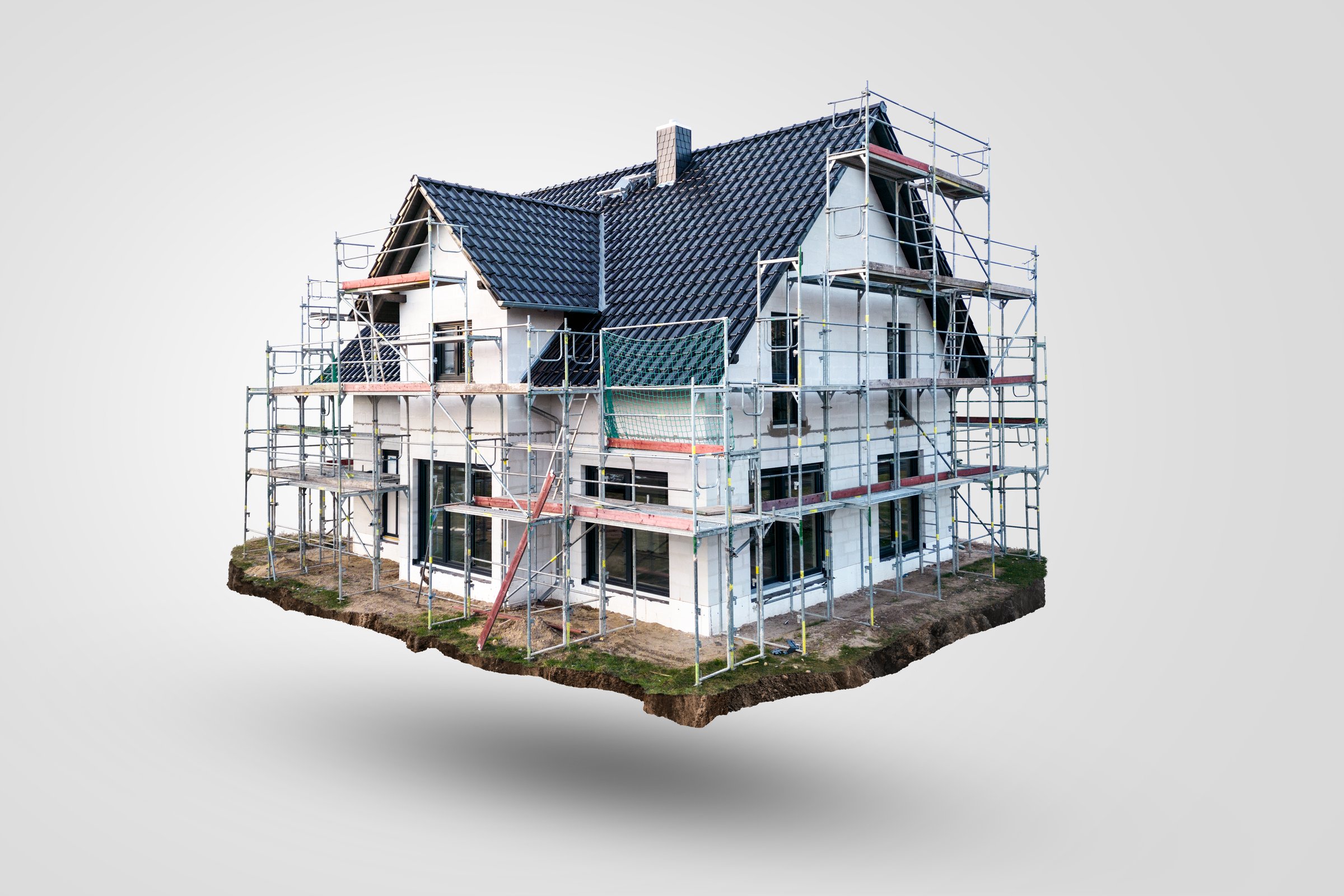Floating single-family home with scaffolding on a neutral background. Real photo of a house isolated from its background.