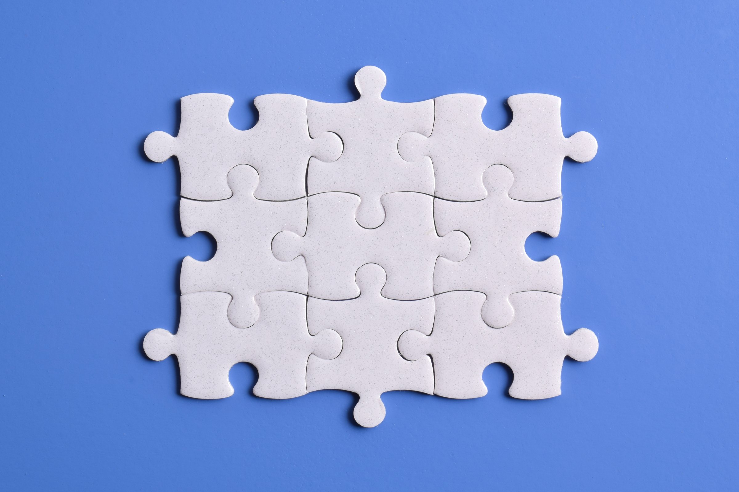 White puzzle pieces isolated on blue background, top view. Space for text