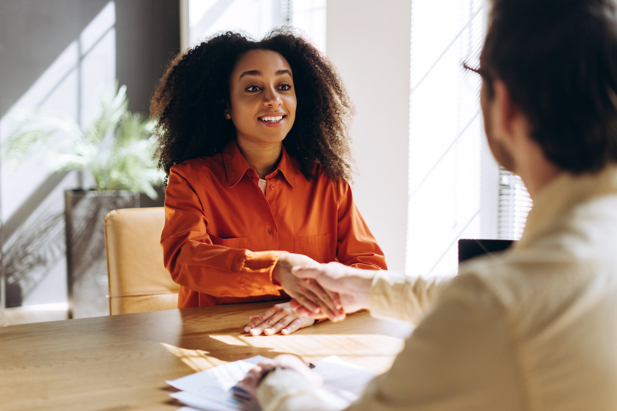 Two professionals shaking hands after a successful job interview, celebrating the happy moment of a businesswoman getting hired, highlighting the essence of employment and human resources