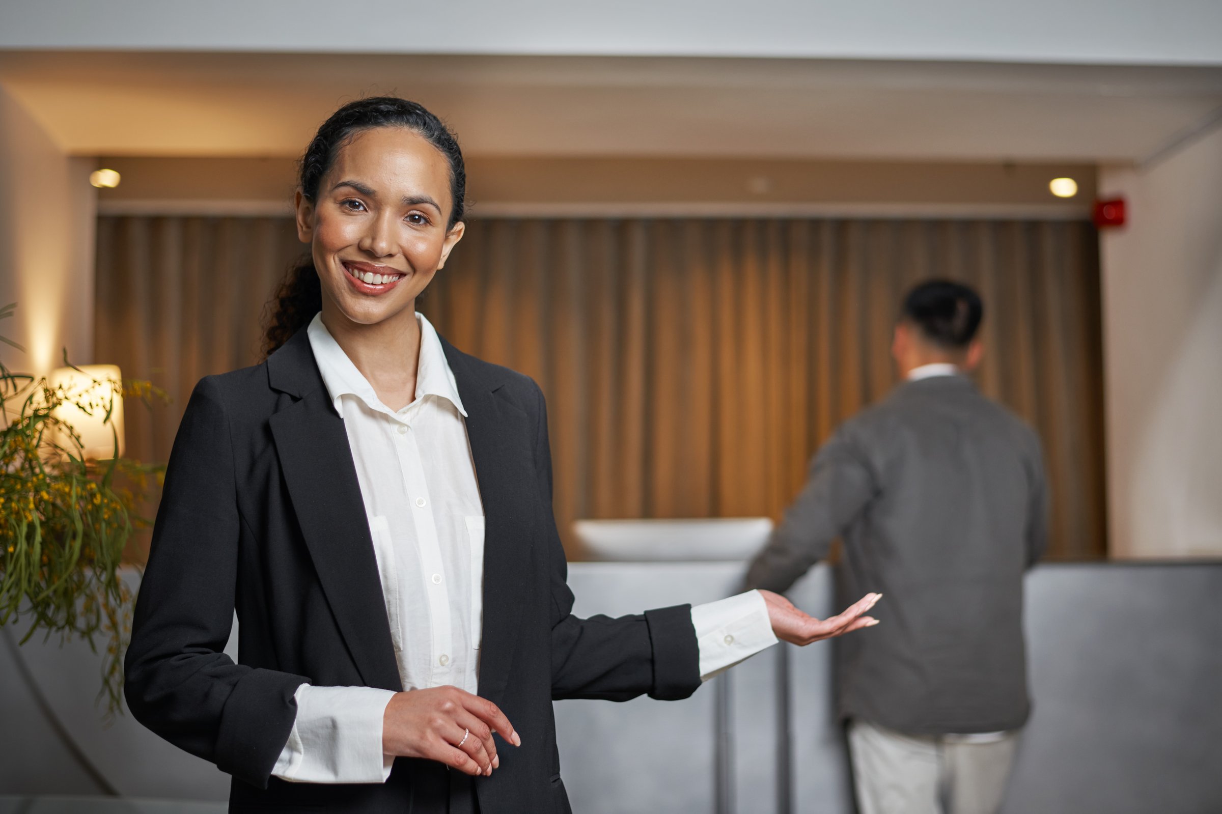 A professional hotel receptionist warmly greets a guest in an elegant lobby setting