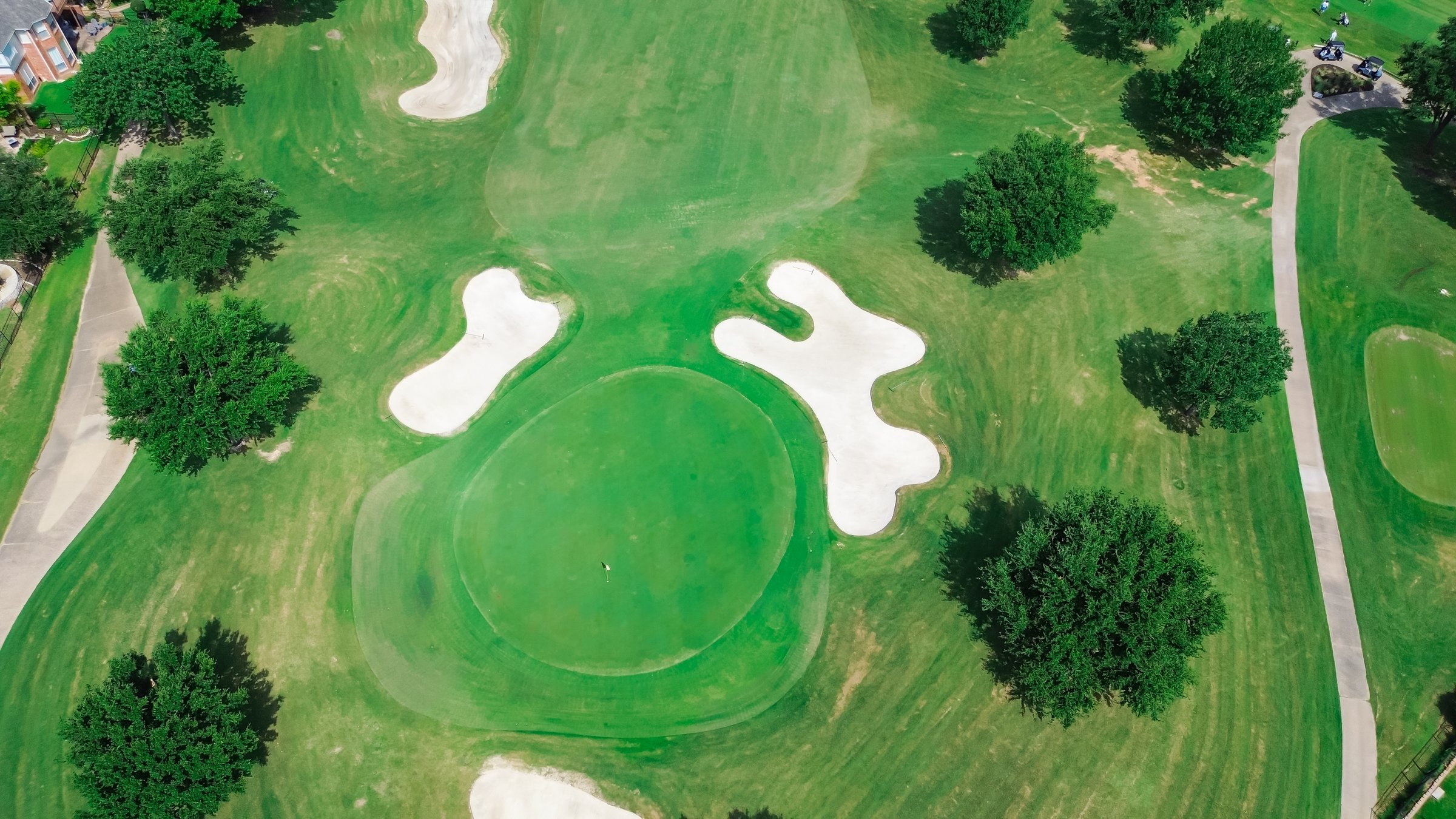Sand trap bunkers depression golf course fairway at upscale country club in Plano, Texas, club car, golfers playing, outdoor recreational area situated in wealthy residential neighborhood, aerial. USA
