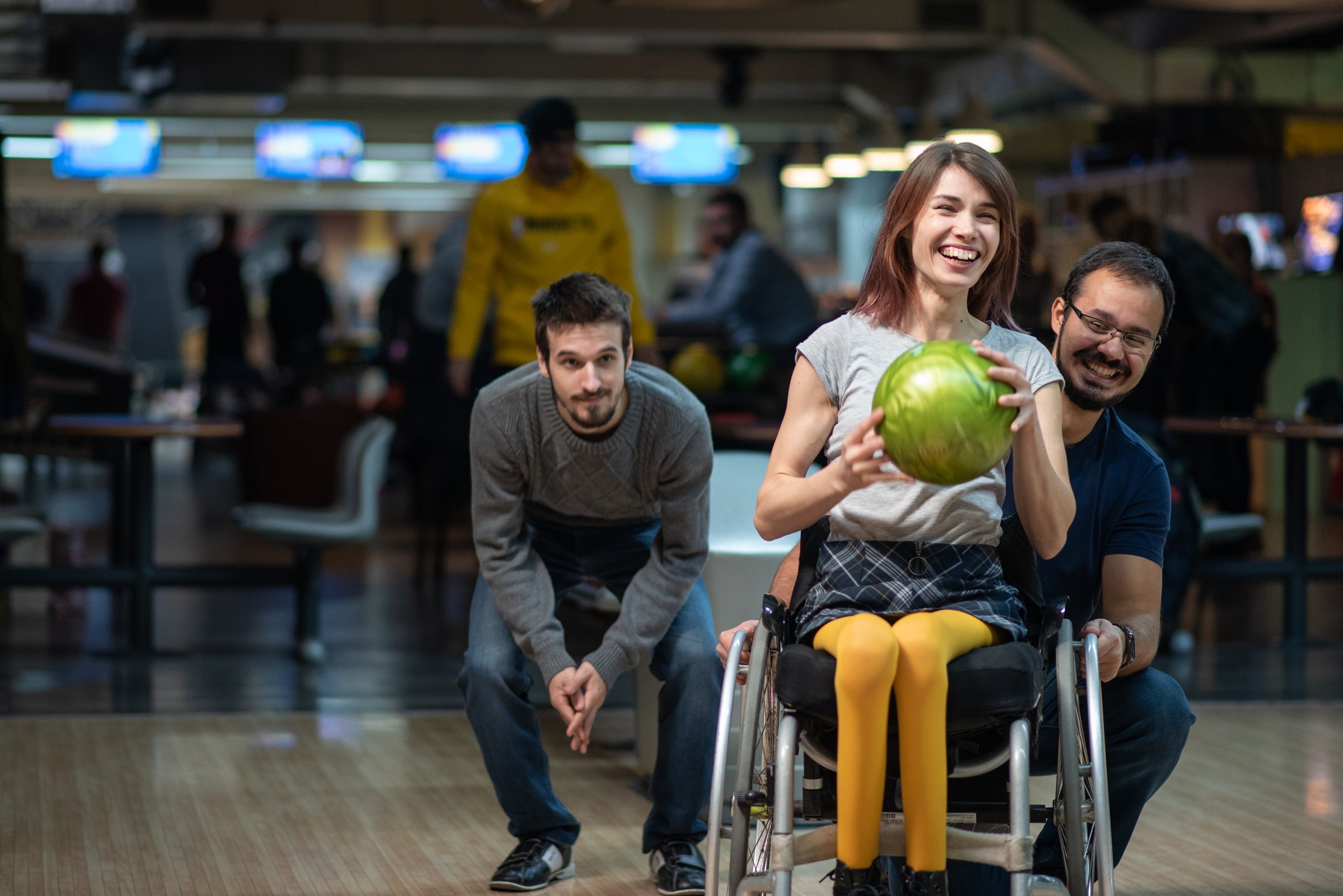 Disabled woman in a wheelchair bowling with friends