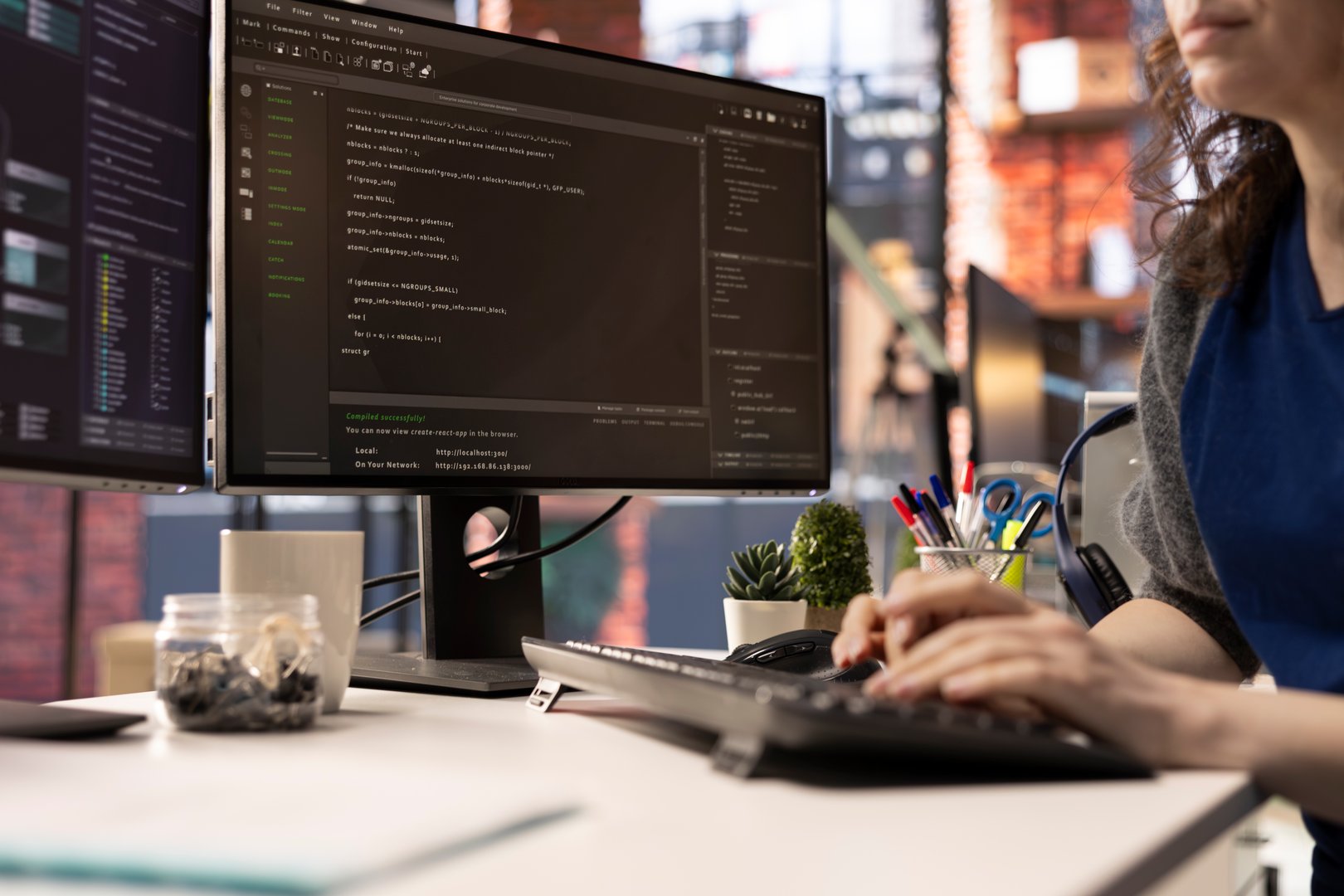Technician at the office looking at UI on computer monitor and executing programming code. IT freelance worker using coding application to write and test code in modern apartment.
