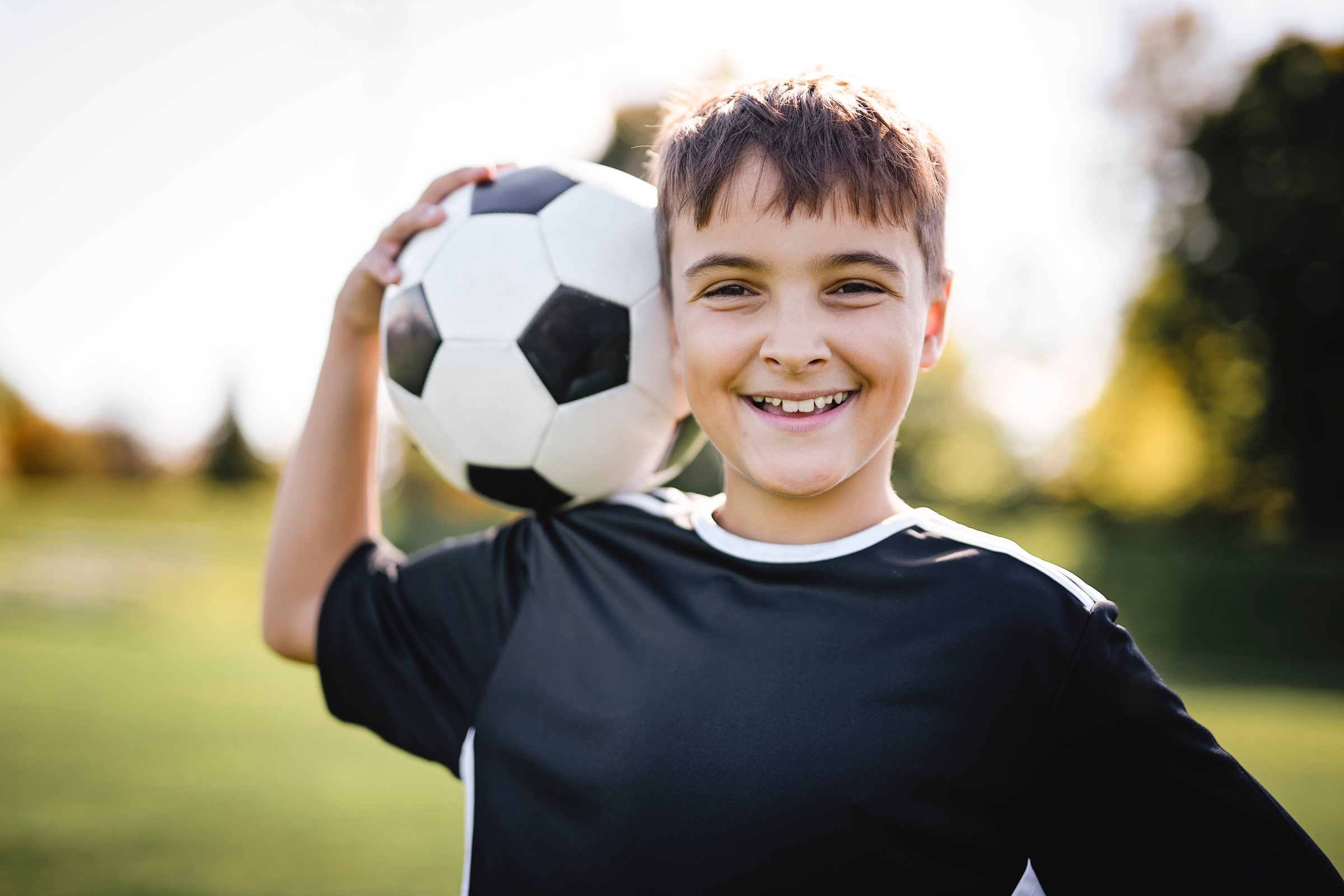 Sport, boy and ball on head with football on field for balance, trick practice and exercise for competition match. Soccer player, person and playing with header for coordination training and fitness
