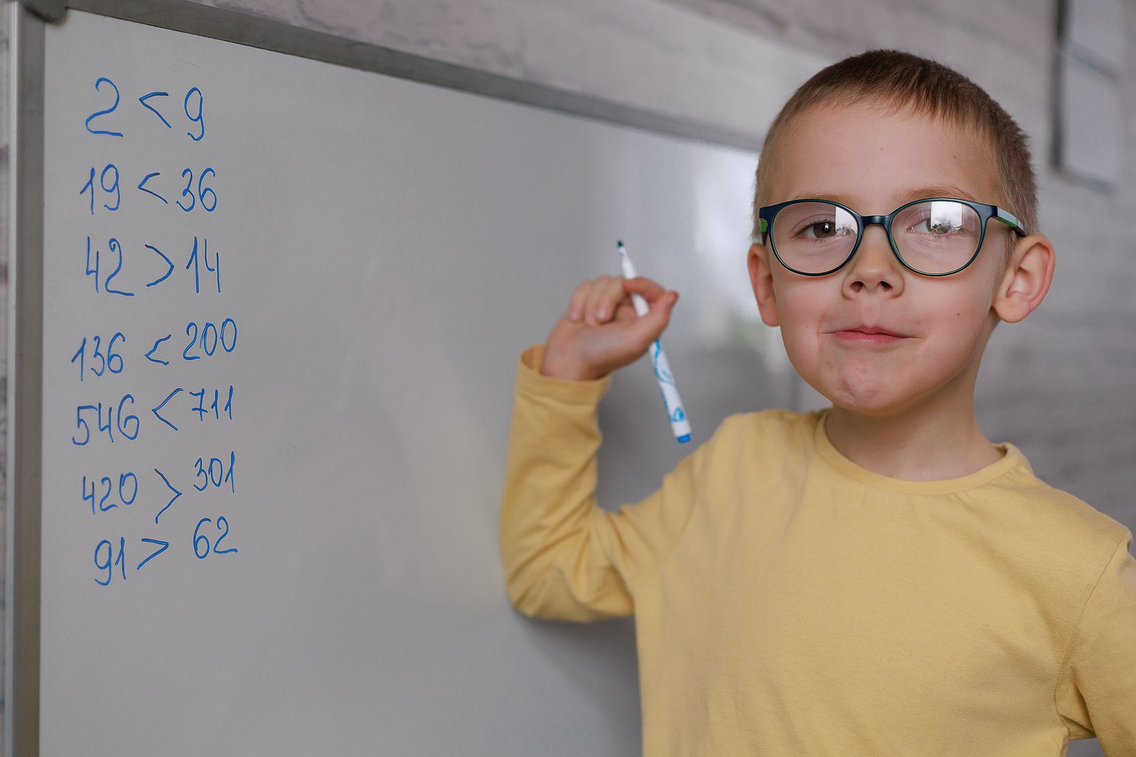 Child standing at whiteboard showing completed work with confidence