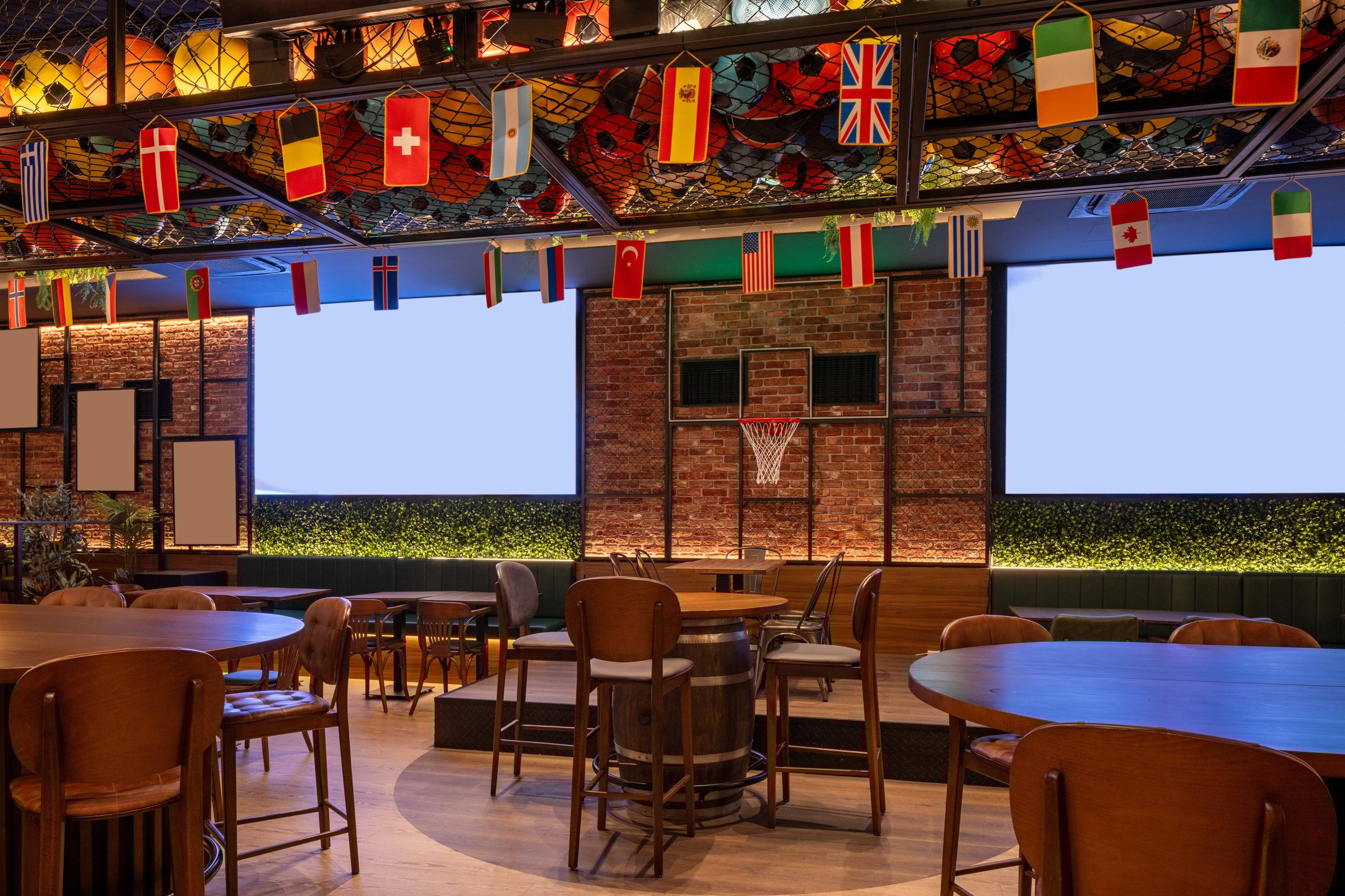 Modern sports bar interior with wooden tables, flags, and basketball hoop