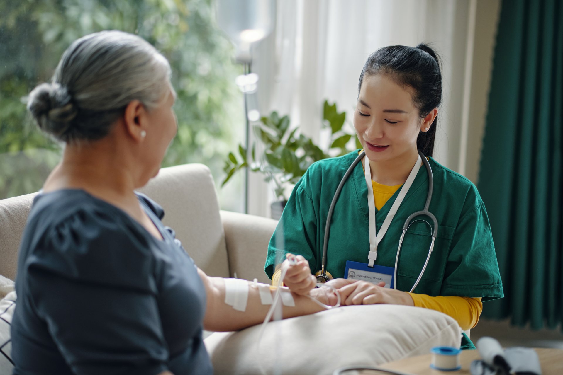 Senior woman getting intravenous therapy while nurse making iv drip