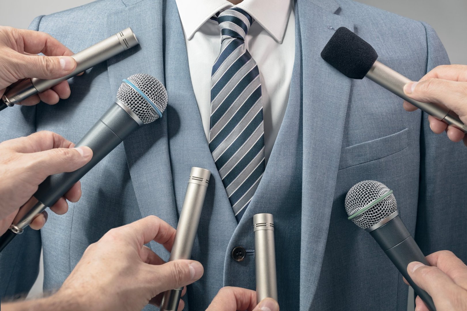 Press conference with media microphones held in front of business man, spokesman or politician making an announcement or statement