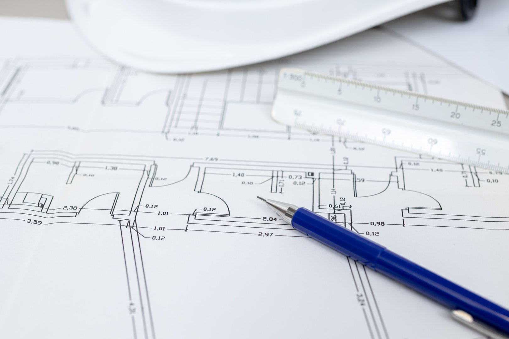 A close-up of blueprints with a blue pen resting on them.