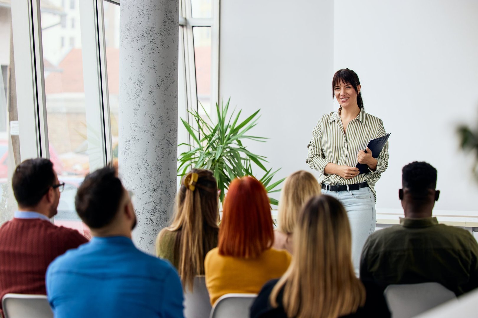 Woman speaking to adults seated indoors, creating interactive and professional engagement.
