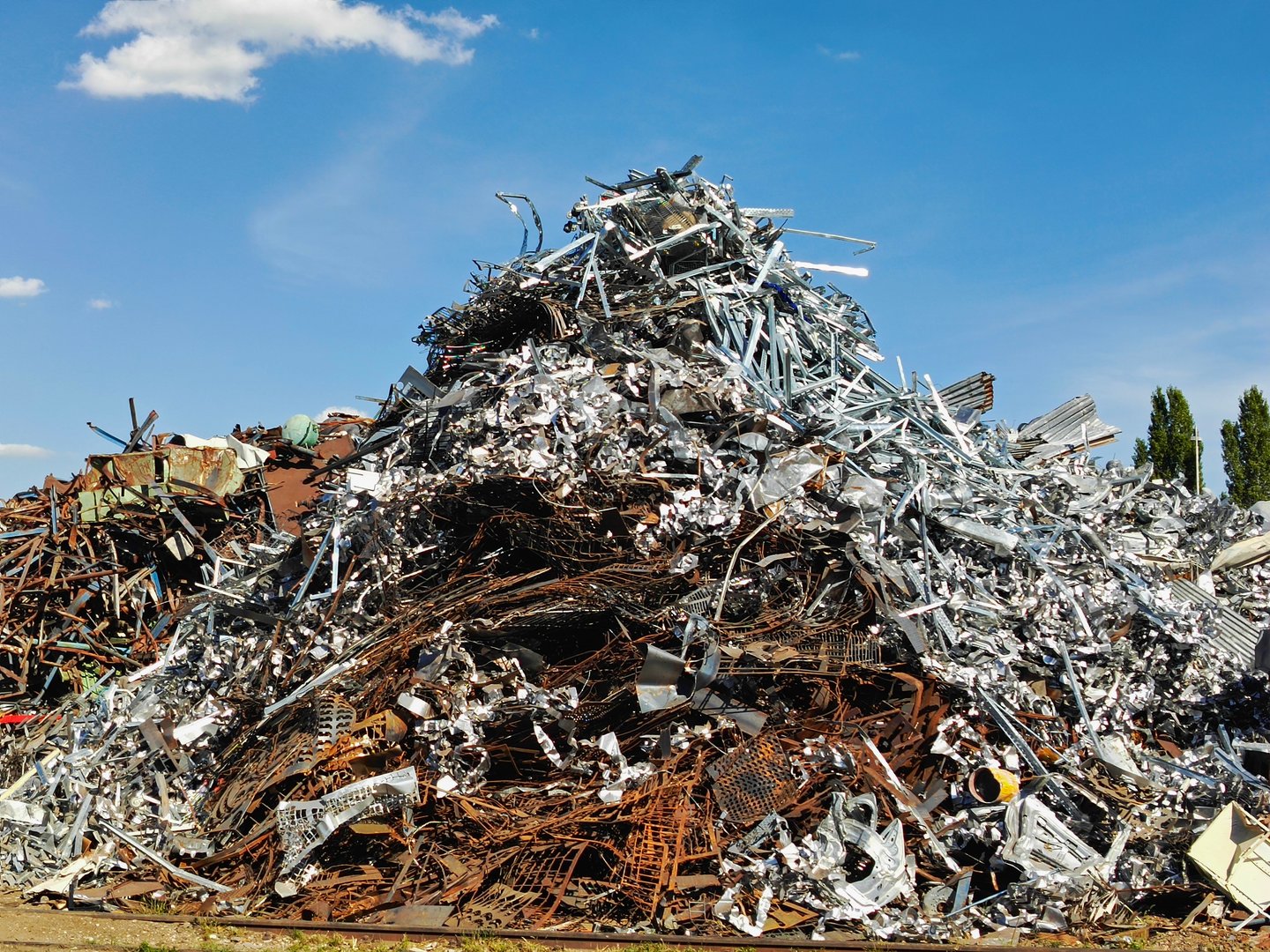 Huge mound of mixed scrap metal and rusty steel waste in a junkyard under blue sky, symbolizing recycling, reuse, and industry. High quality photo