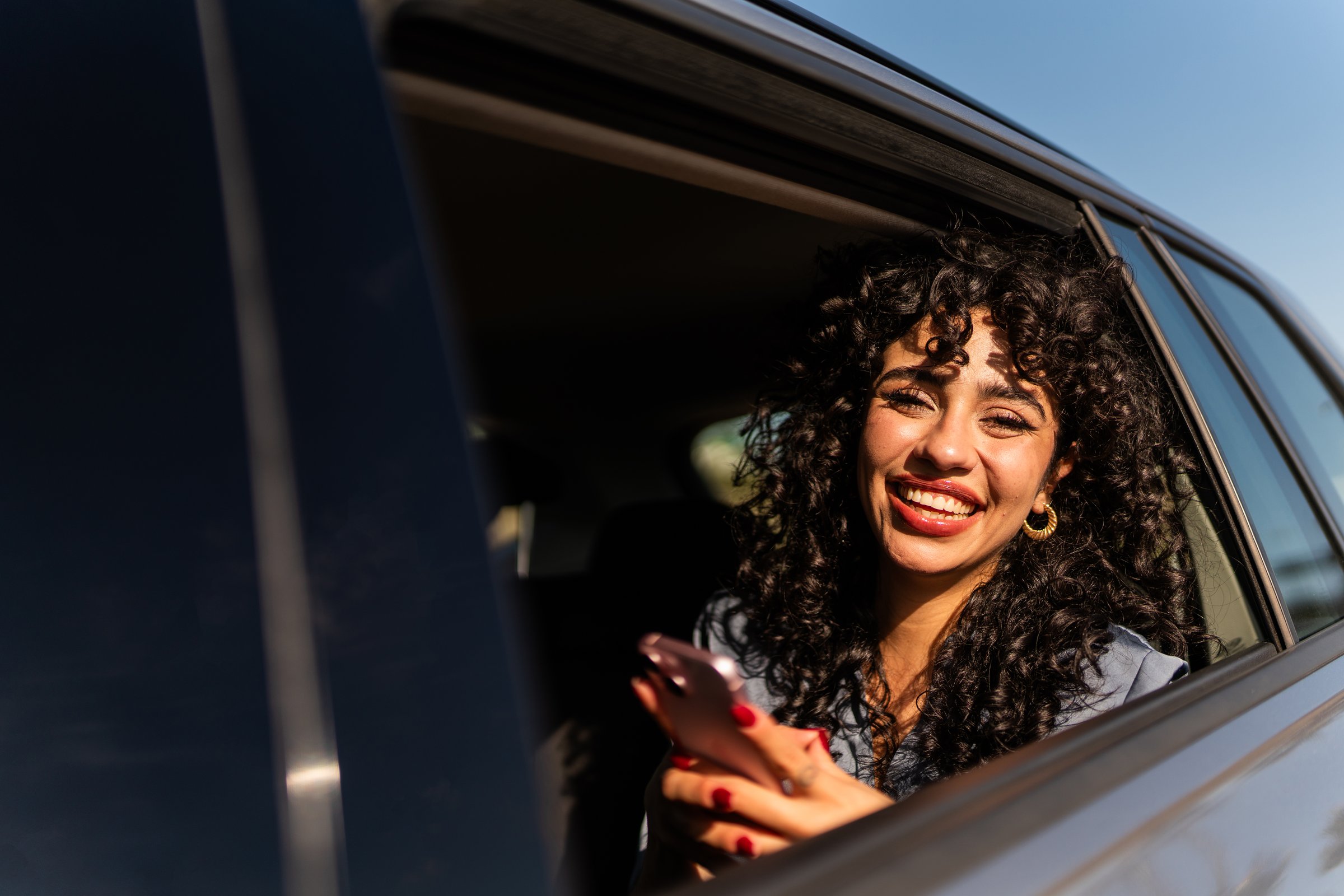 Portrait of young woman using mobile phone inside a taxi