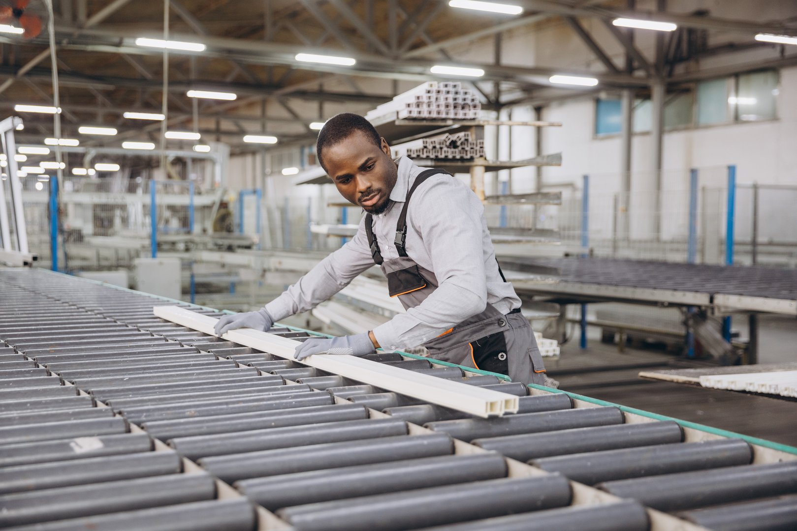 African american factory worker placing pvc window frame on production line in a modern window and door factory