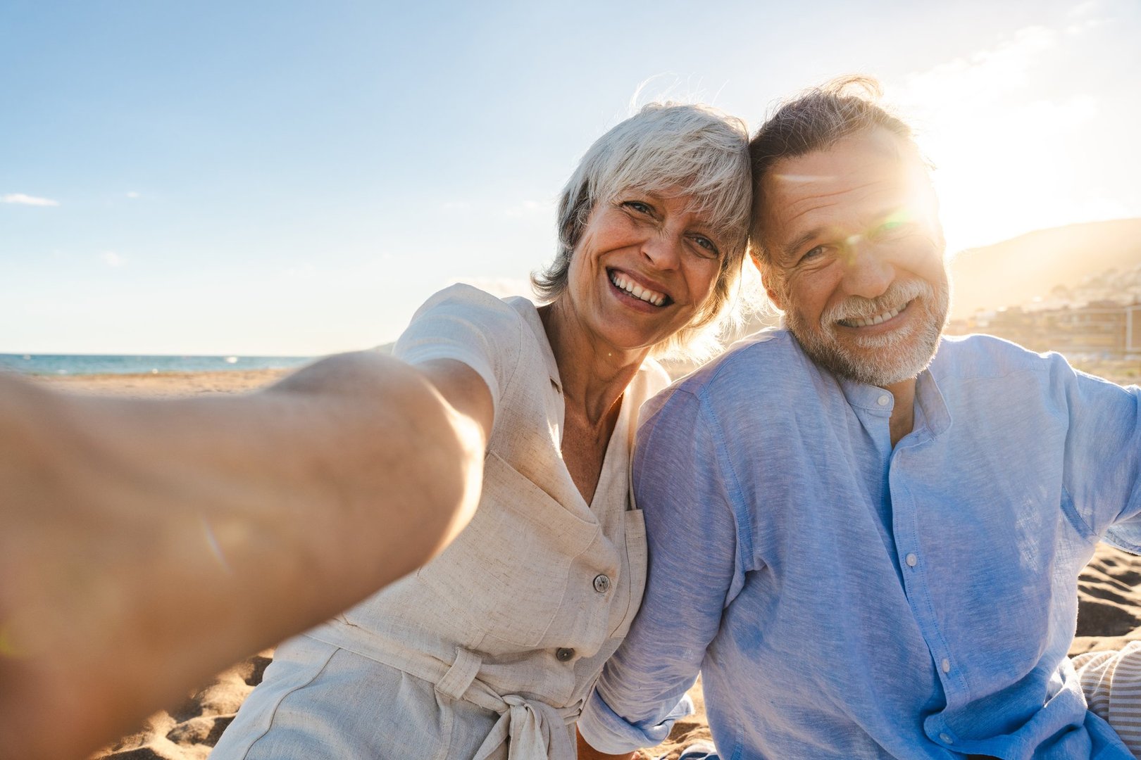Beautiful happy senior couple dating at the seaside during summertime - Mature married couple in love bonding outdoors at the beach, concepts about elderly lifestyle, relationship and quality of life