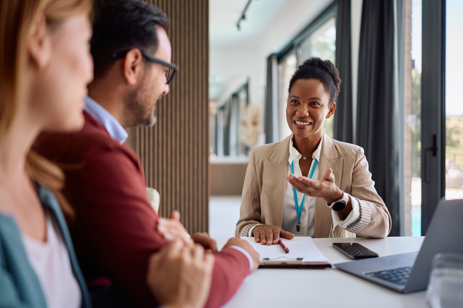 Happy African American real estate agent advising a couple during a meeting.