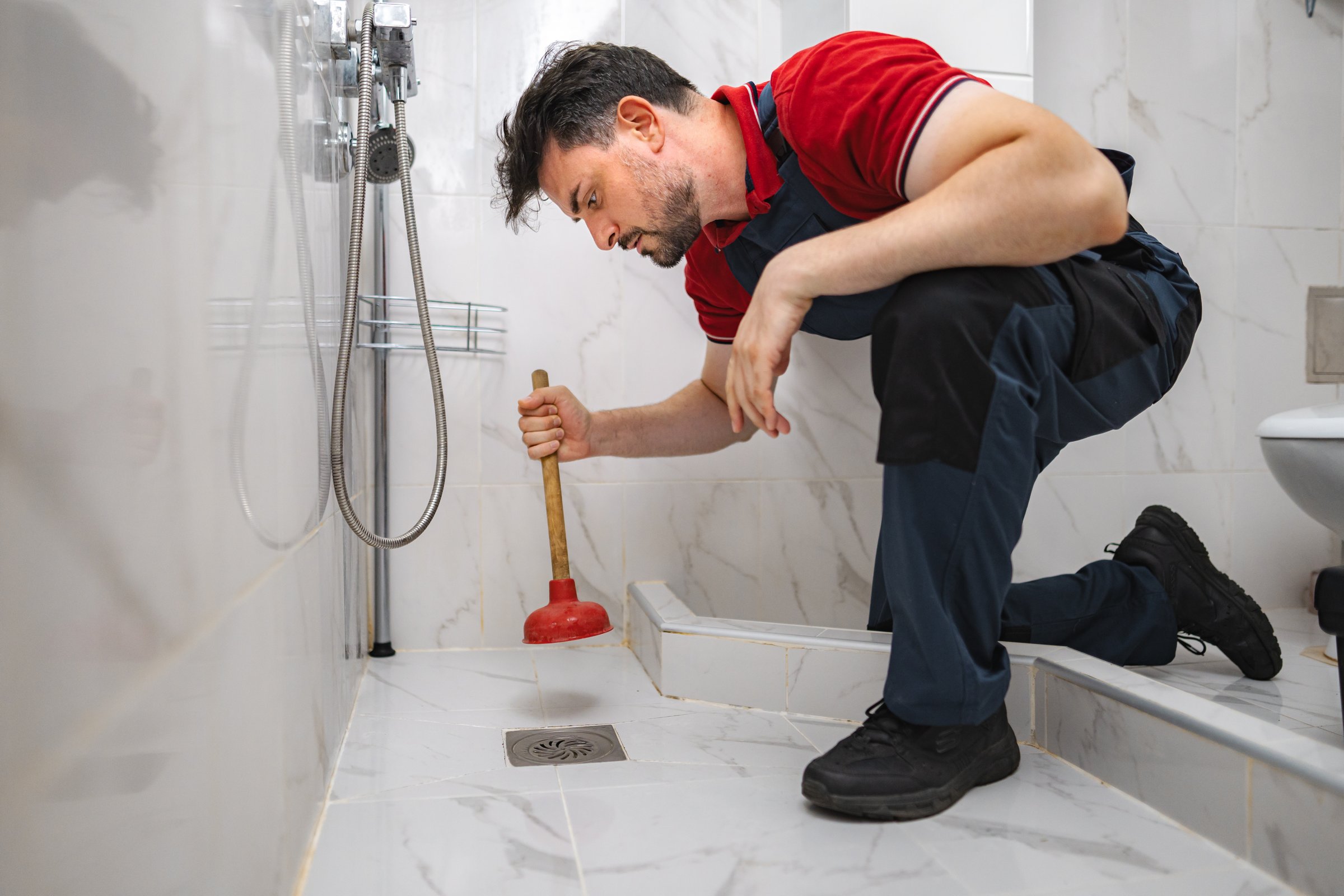 Plumber unclogging toilet