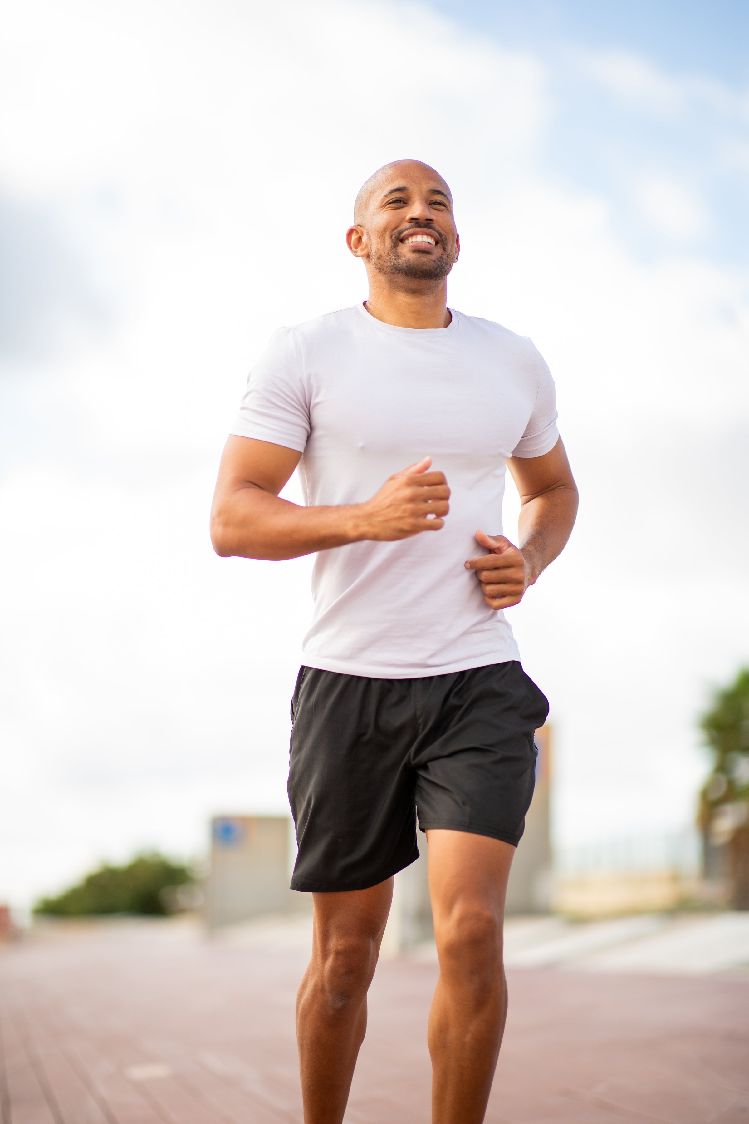 confident and determined jogger enjoying a solo run under a clear sky. The smile on his face reflects the joy of fitness and the freedom of outdoor exercise.