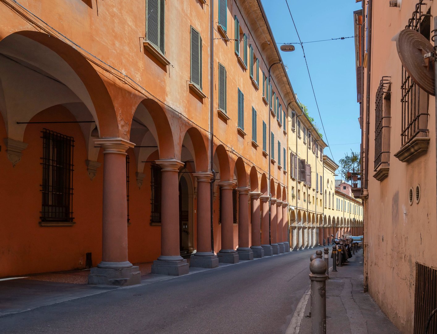 Porticoes and colonnades of Bologna, Italy, Emilia-Romagna. Streets of the old town. Shadows from columns on a marble street.