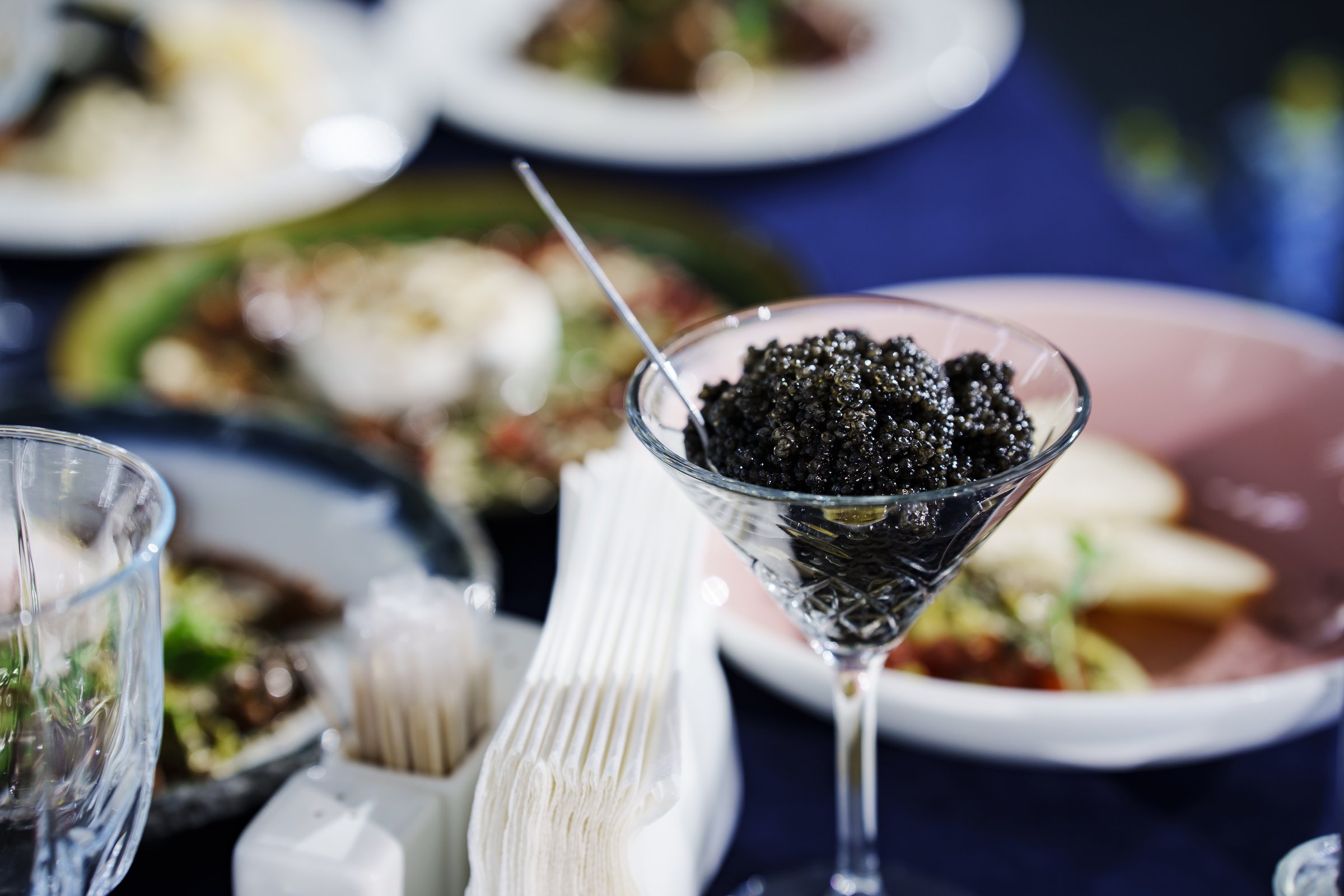 A glass with black caviar and a small spoon caviar. A delicacy fish dish for an expensive banquet.