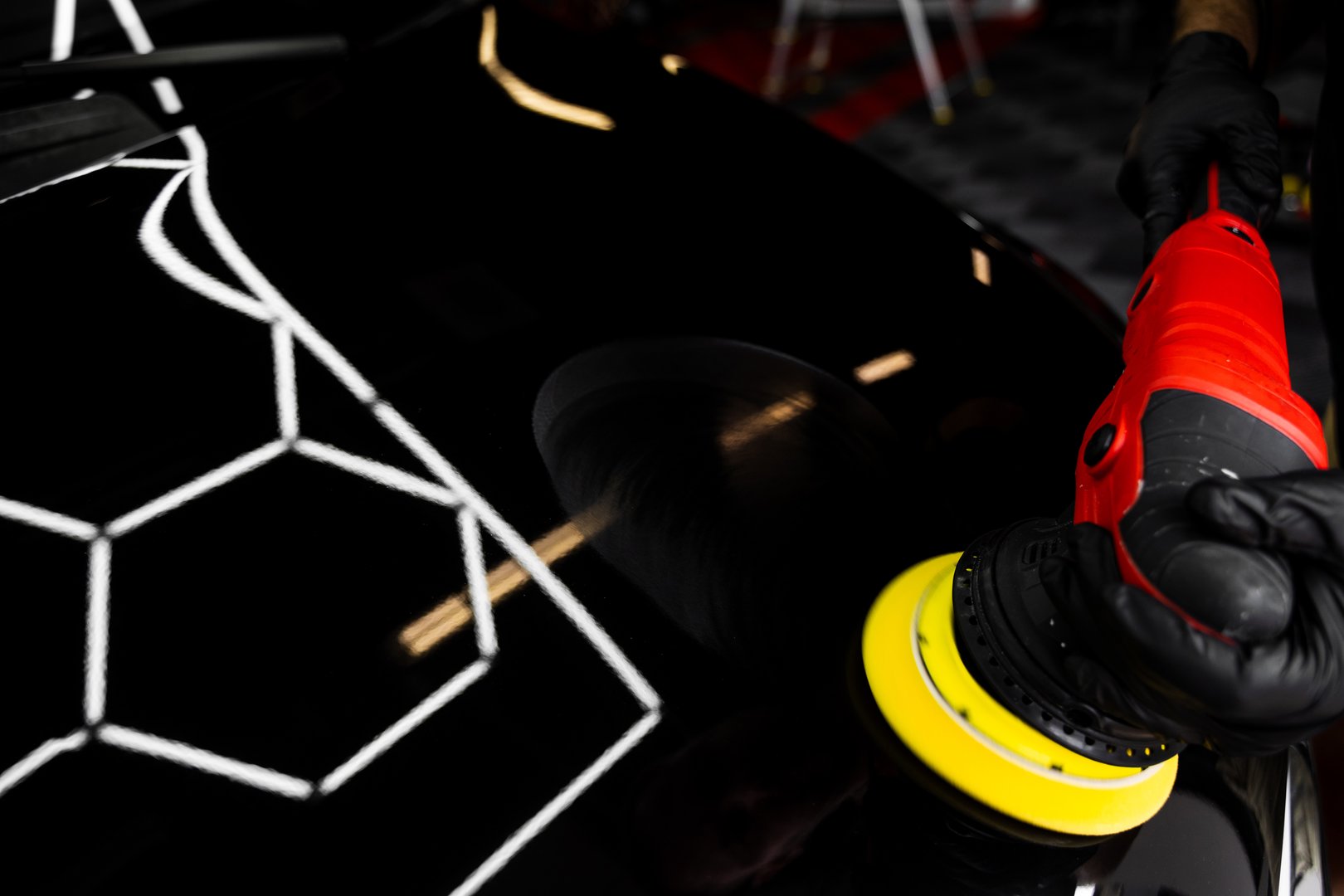 Paint polishing in active motion. Detailing car for sealant or ceramic application. Paint polishing to eliminate swirl marks and restore deep gloss. Car hood being polished with yellow pad