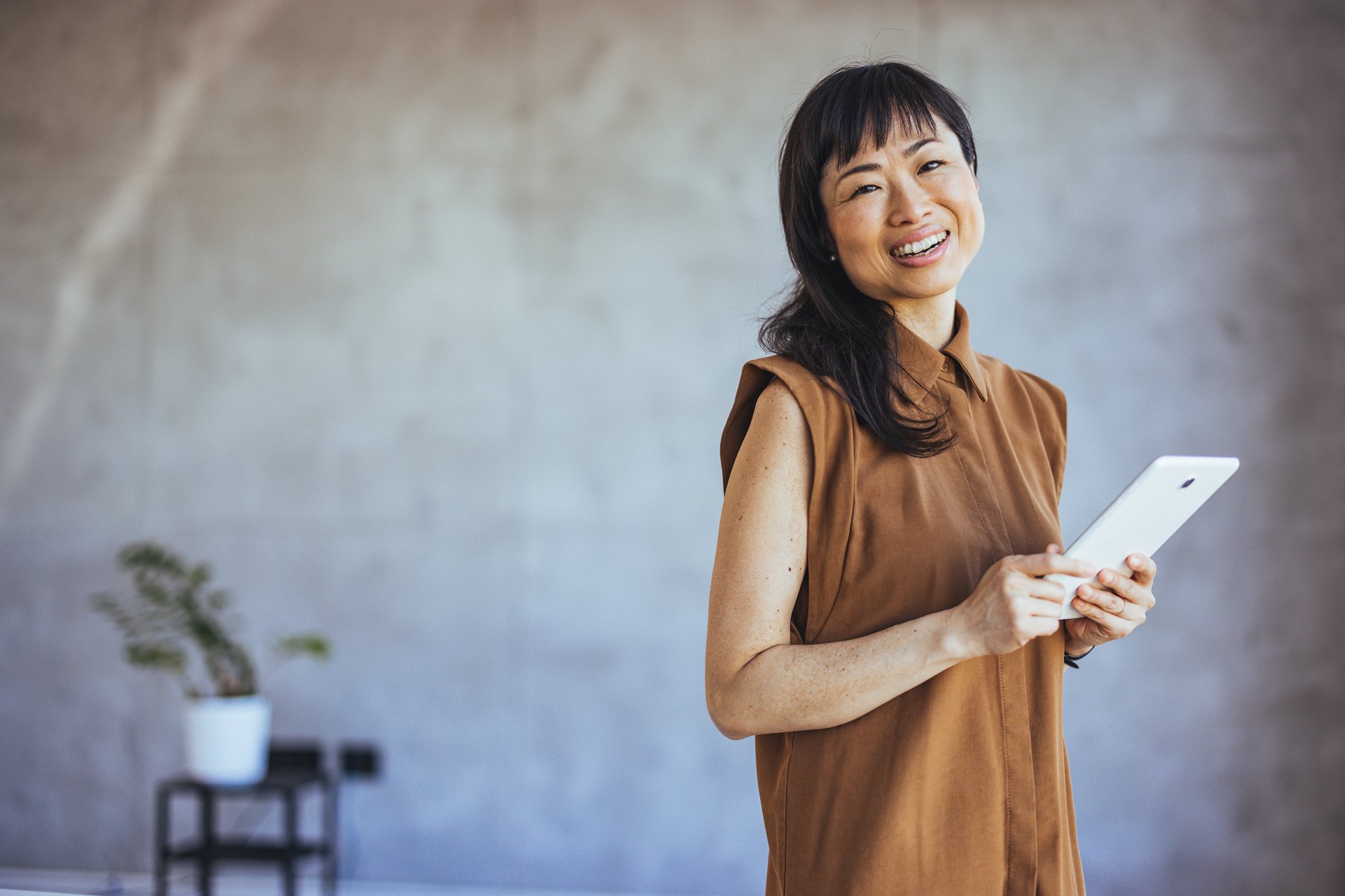 Portrait of a young asian entrepreneur. Portrait young Asian businesswoman holding tablet/smartphone in formal suit in office with copy space. Image of an asian businesswoman