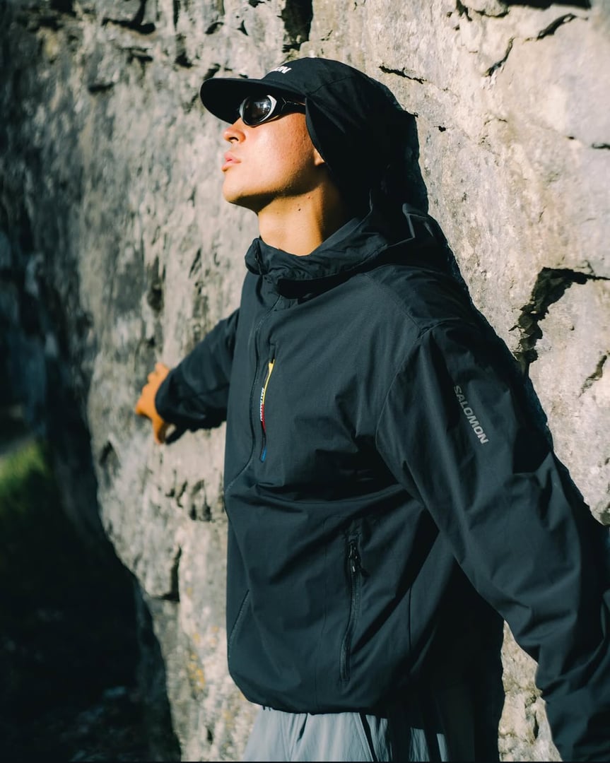 Outdoor fashion model wearing Salomon gear, hat and sunglasses in lifestyle campaign