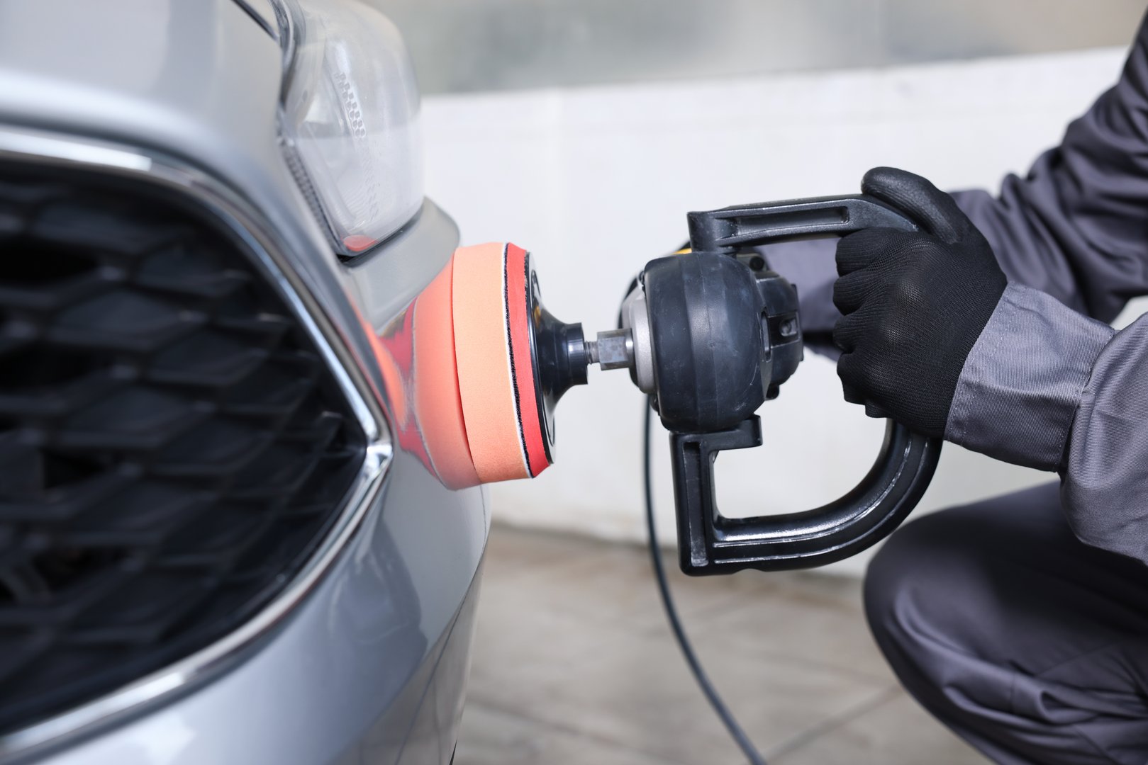 Man polishing car with orbital polisher indoors, closeup