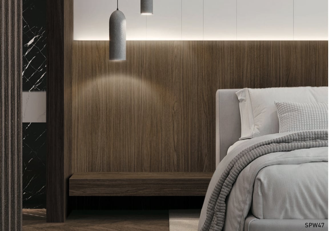 Modern bedroom with a wooden accent wall, hanging pendant lights, and a neatly made bed with grey bedding.