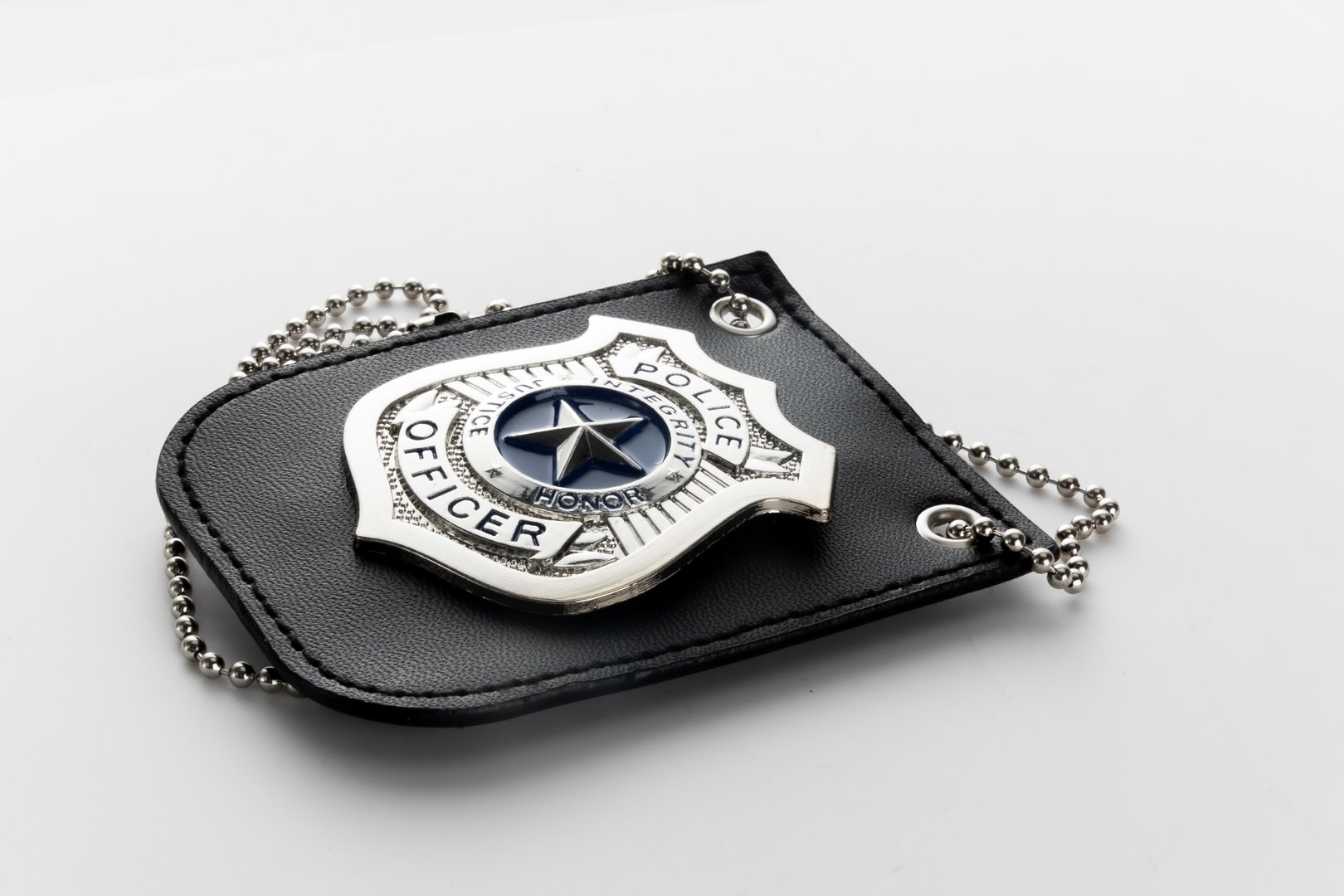 Police badge on black leather wallet, contrasting colors, symbol of authority and law enforcement, textured surface, hint of reflection.