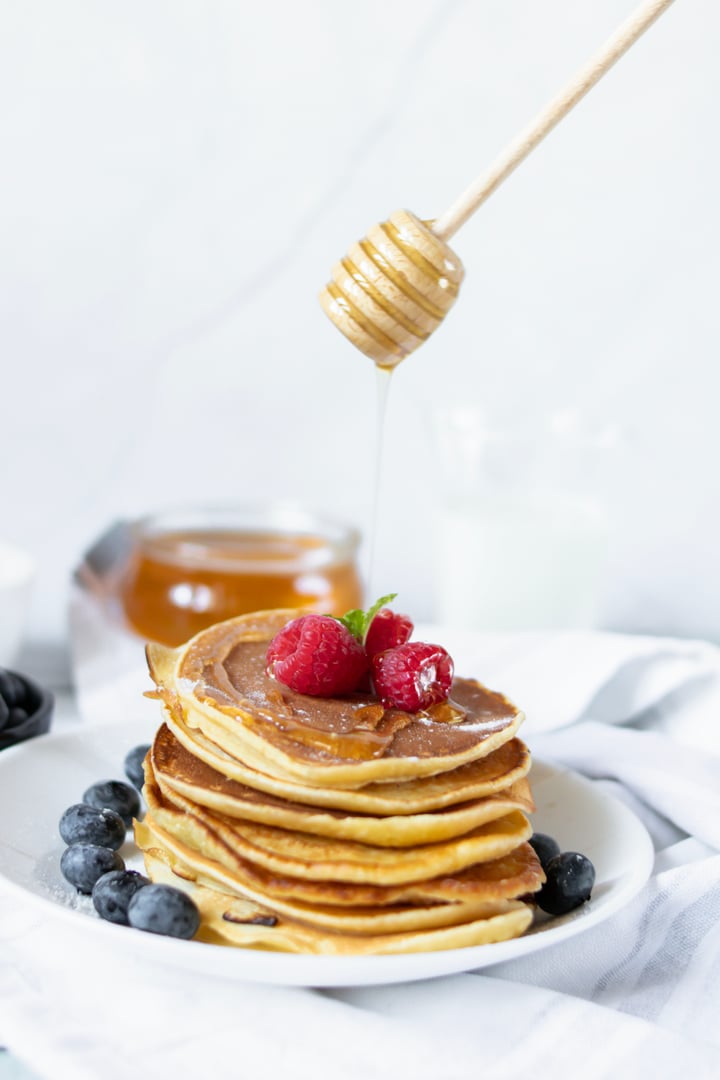 Pancakes with fresh berries and honey. on a wooden background.