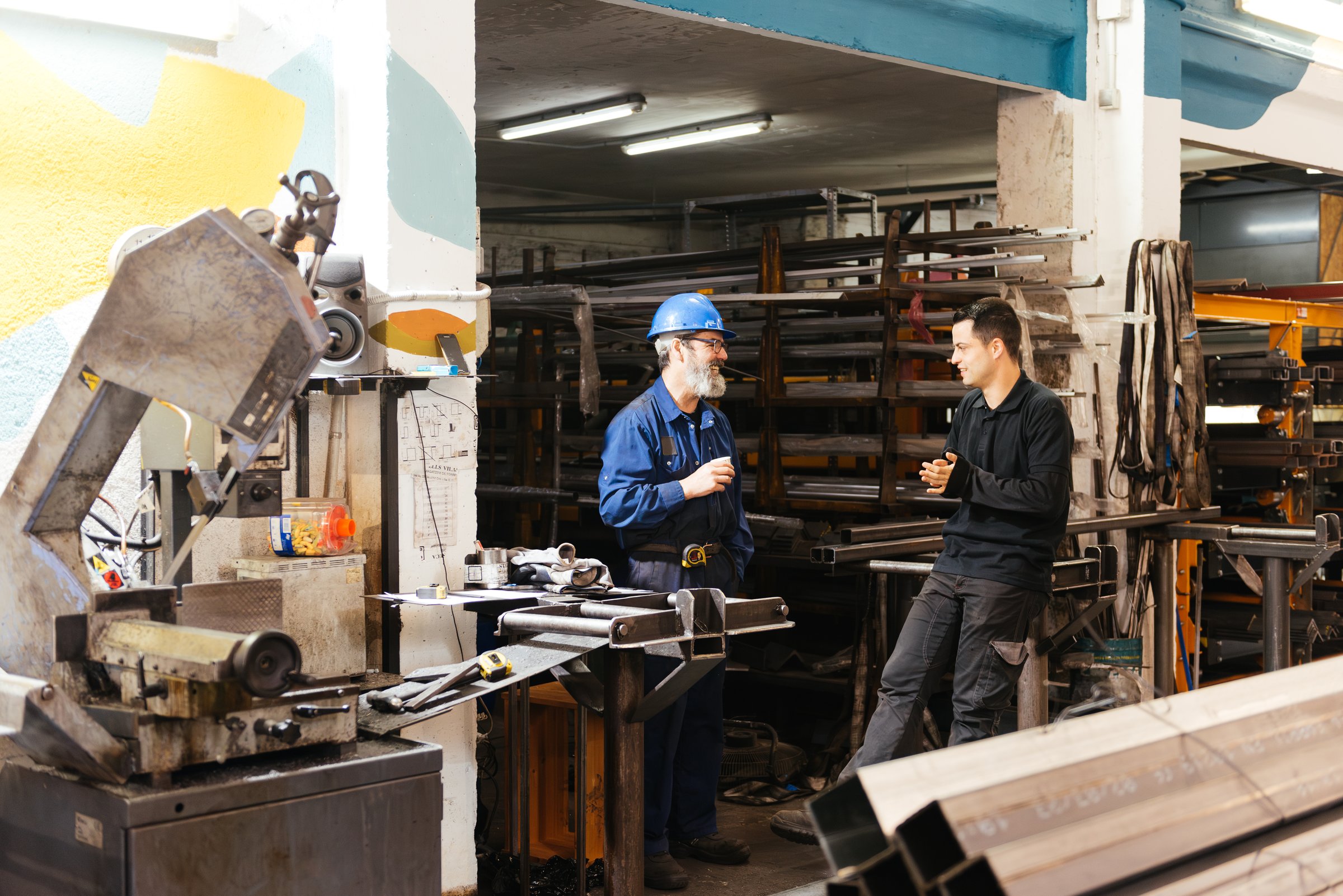 Side view of men standing near industrial facility discussing work issues while looking at each other in warehouse