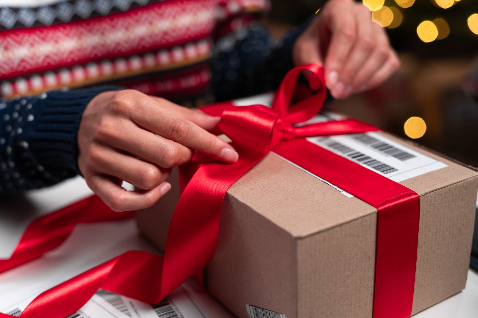 Merry Christmas shipping delivery concept. Santa Claus packing present box wrapping gift with red ribbon preparing post shipping delivery parcel. Close-up