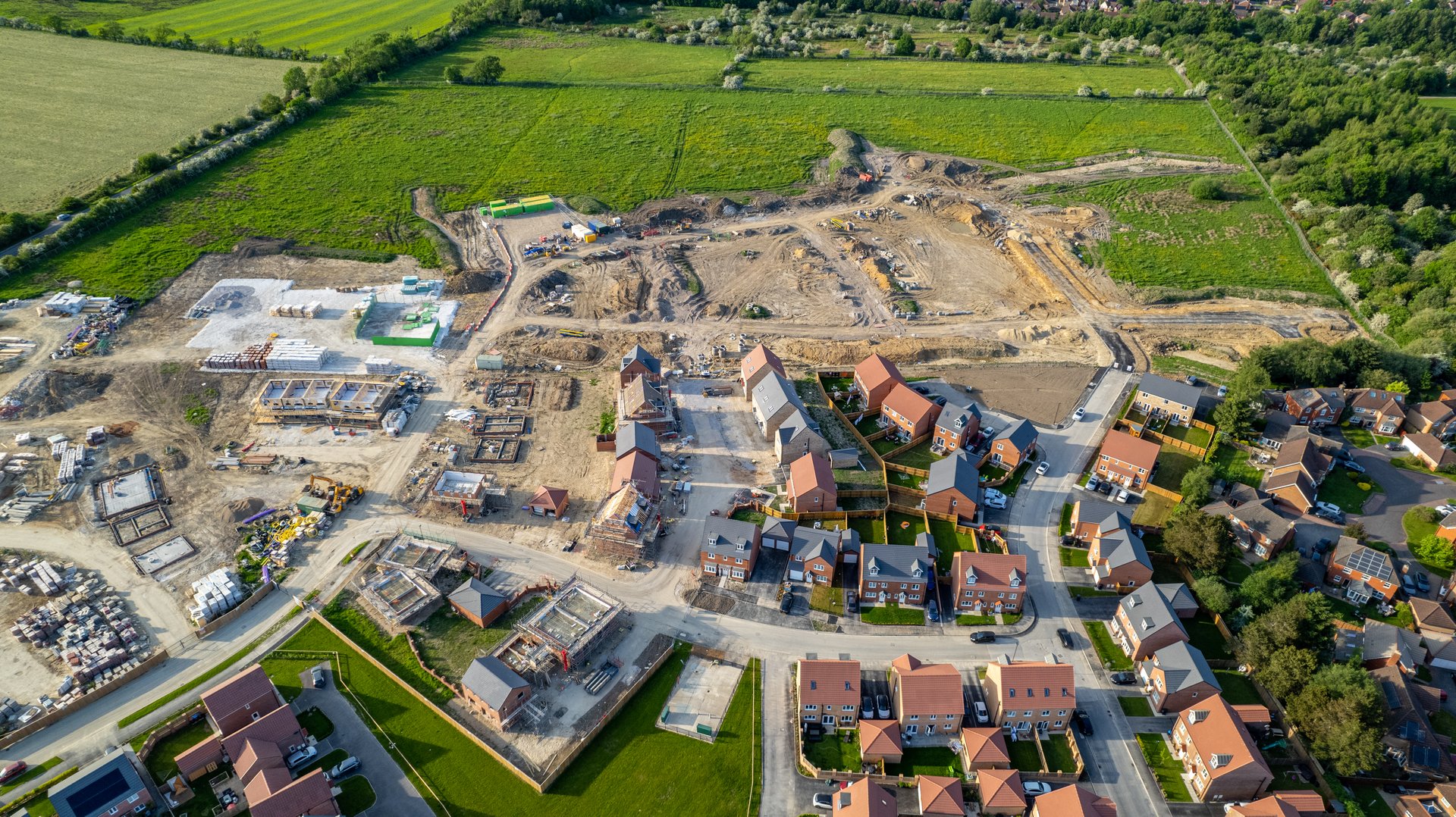 Aerial view of a residential construction site with unfinished houses and building materials, showcasing urban development.