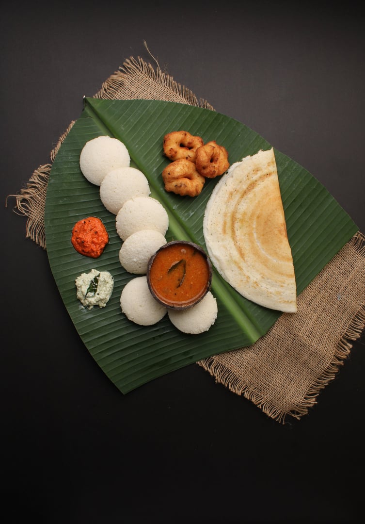 Group of South Indian food like Masala Dosa, Idli, Wada or vada, sambar, served over banana leaf with colourful coconut chutneys