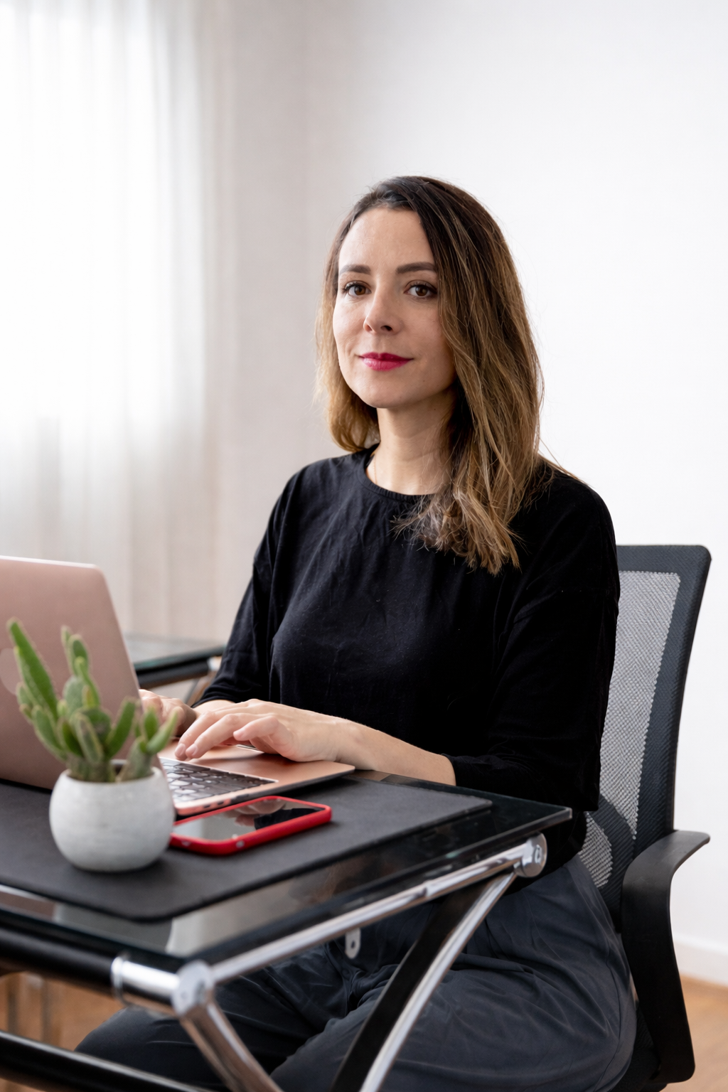 Portrait of female leader standing at corporate firm with arms crossed and smiling at camera.