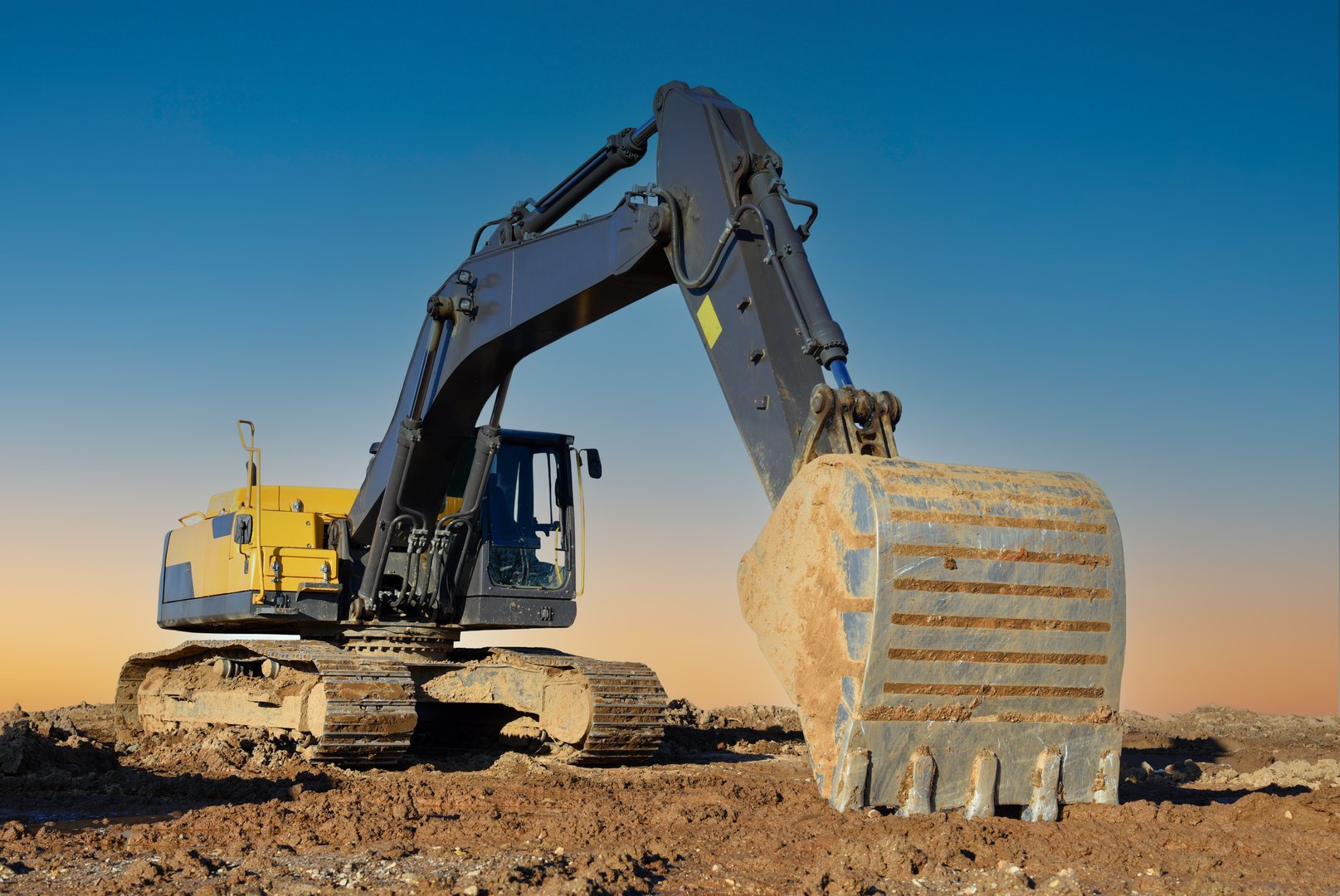 Excavator on earthworks. Construction machinery on groundworks. Open-pit mining. Excavator on sunset. Backhoe dig ground in quarry. Heavy construction equipment on excavation on construction site.