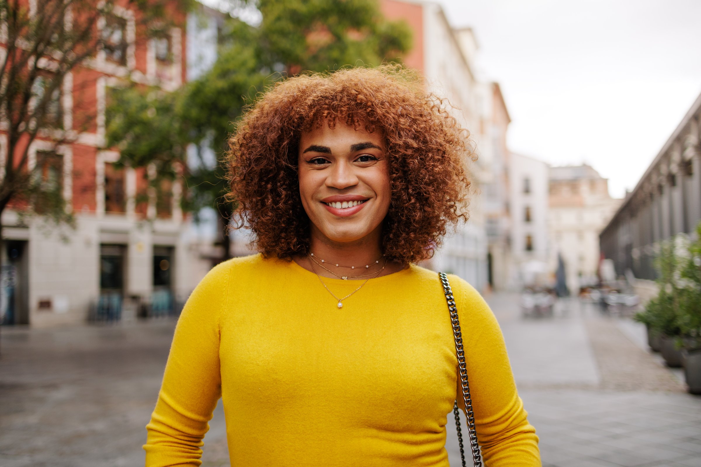 Latin gen z transgender woman smiling to the camera in city street. High quality photo