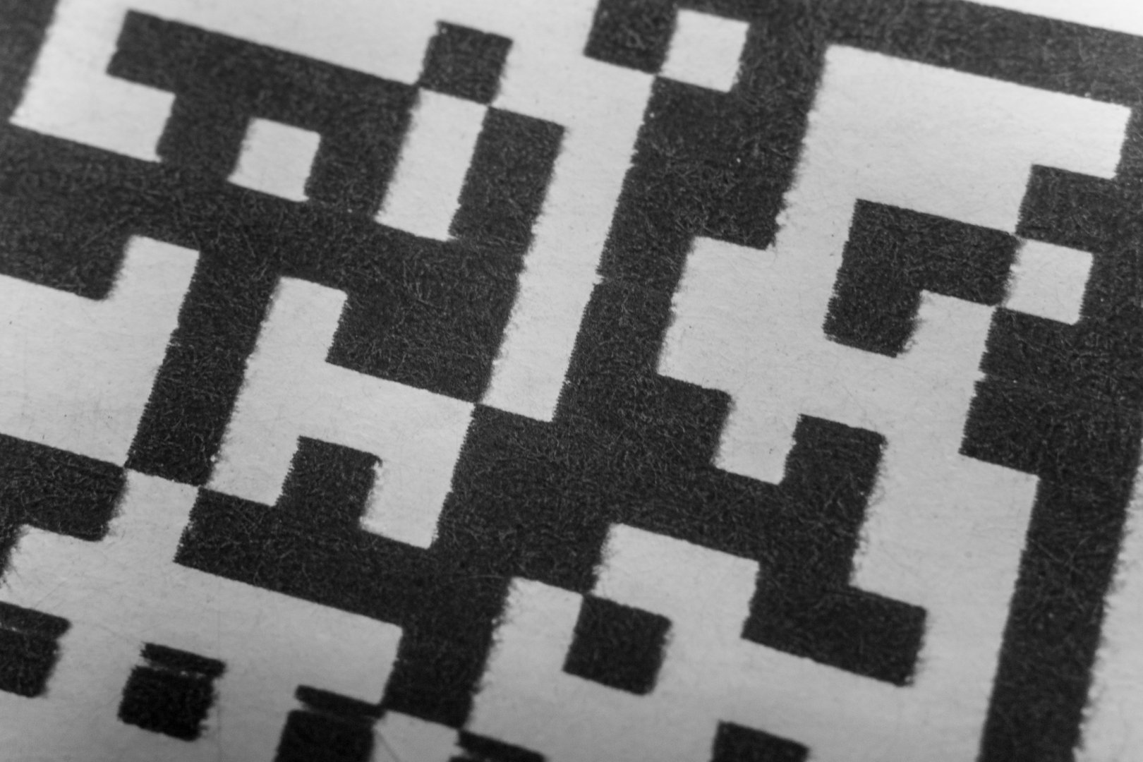 Abstract monochrome close up of isolated printed QR data matrix bar code on white paper label background from material inventory tracking system