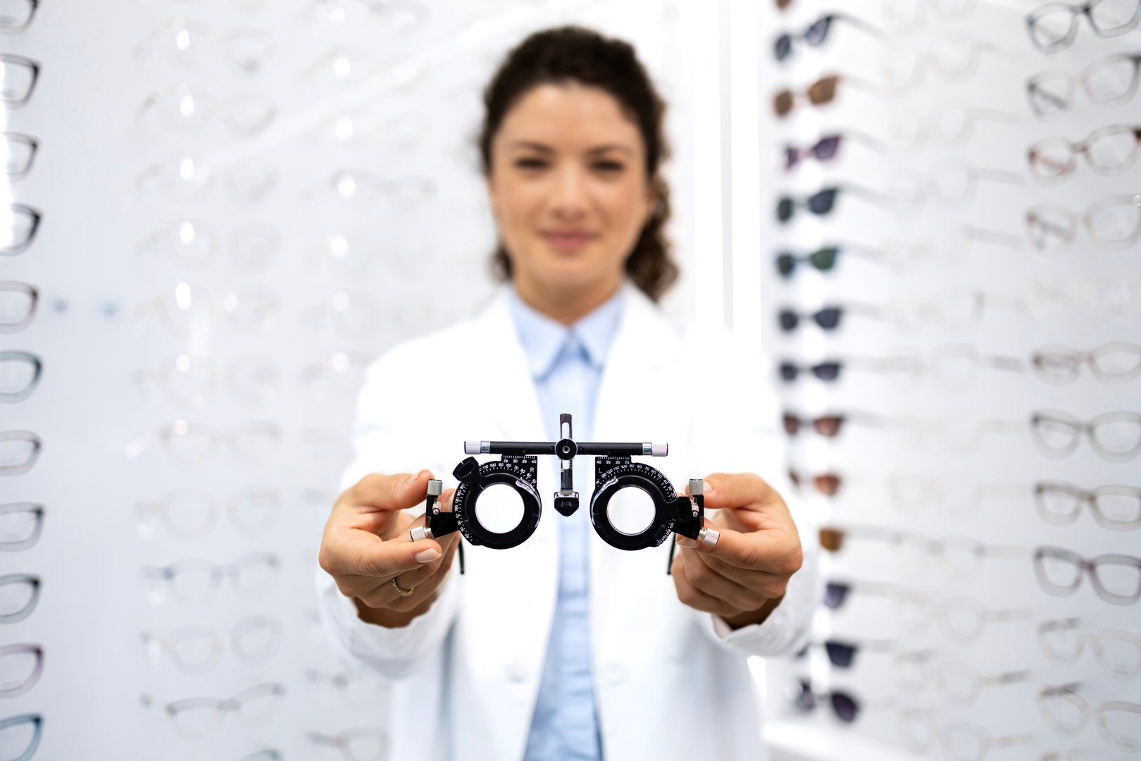 Experienced ophthalmologist holding eyeglass instrument for testing eyesight.